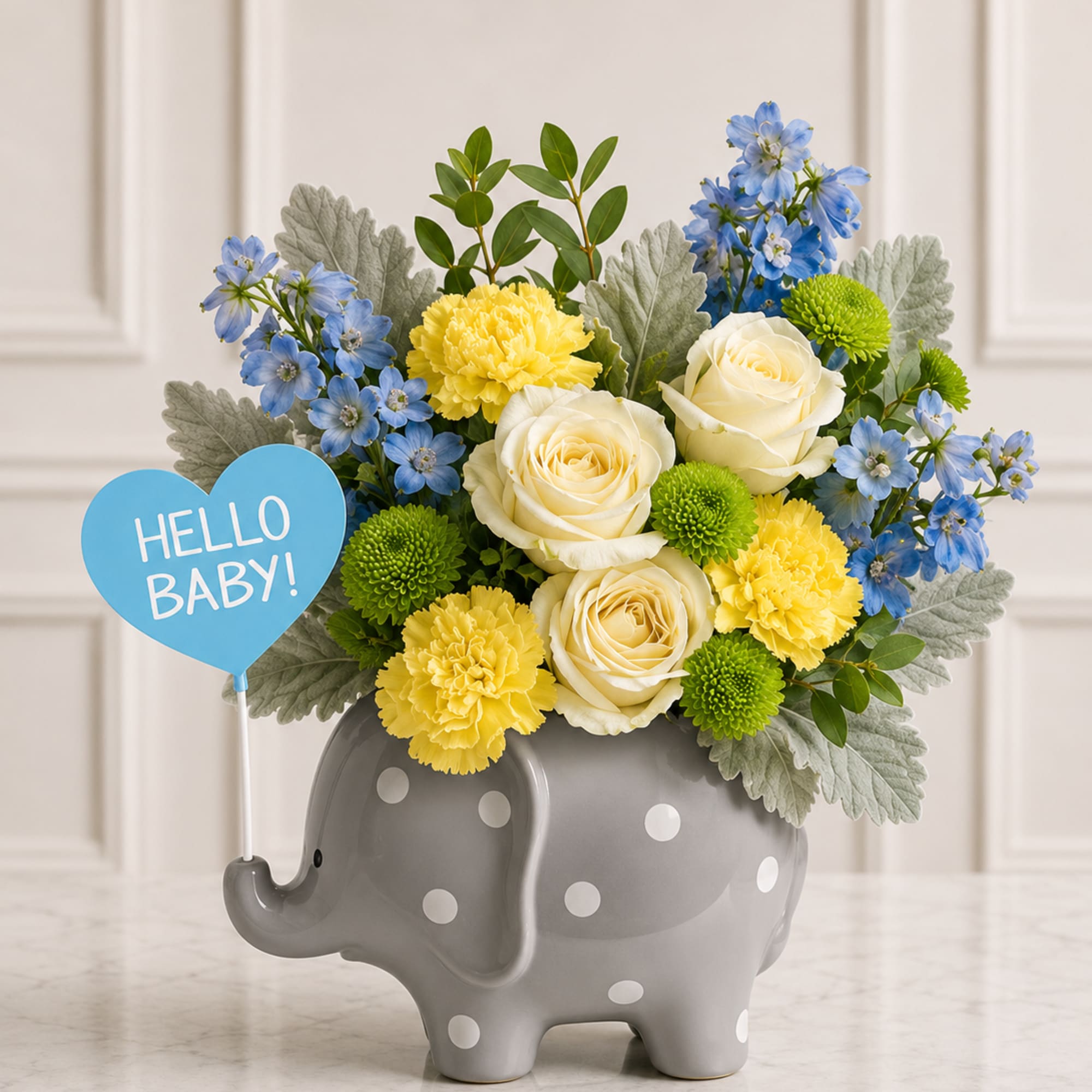 Bouquet of blue, yellow, and white flowers in a gray elephant vase with a "Hello Baby!" sign