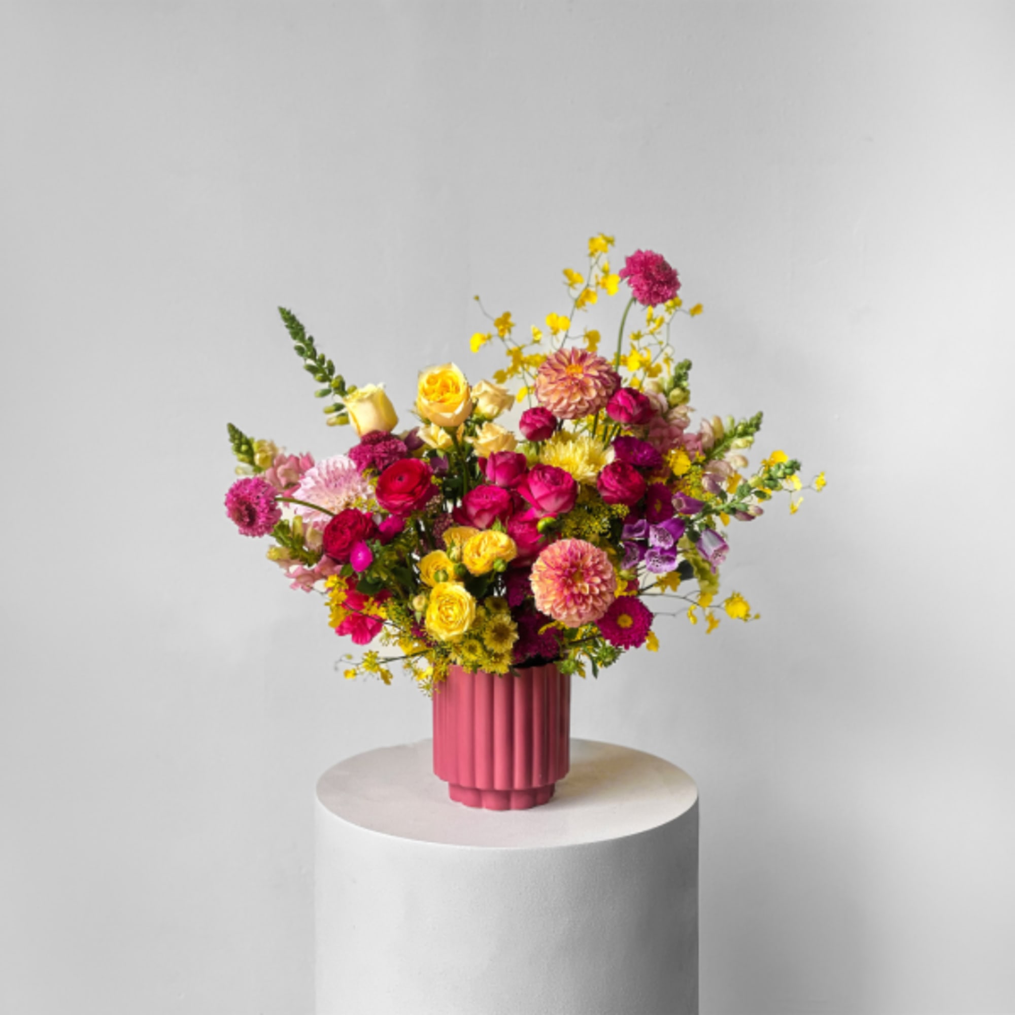 Colorful mixed bouquet in a pink vase on a pedestal