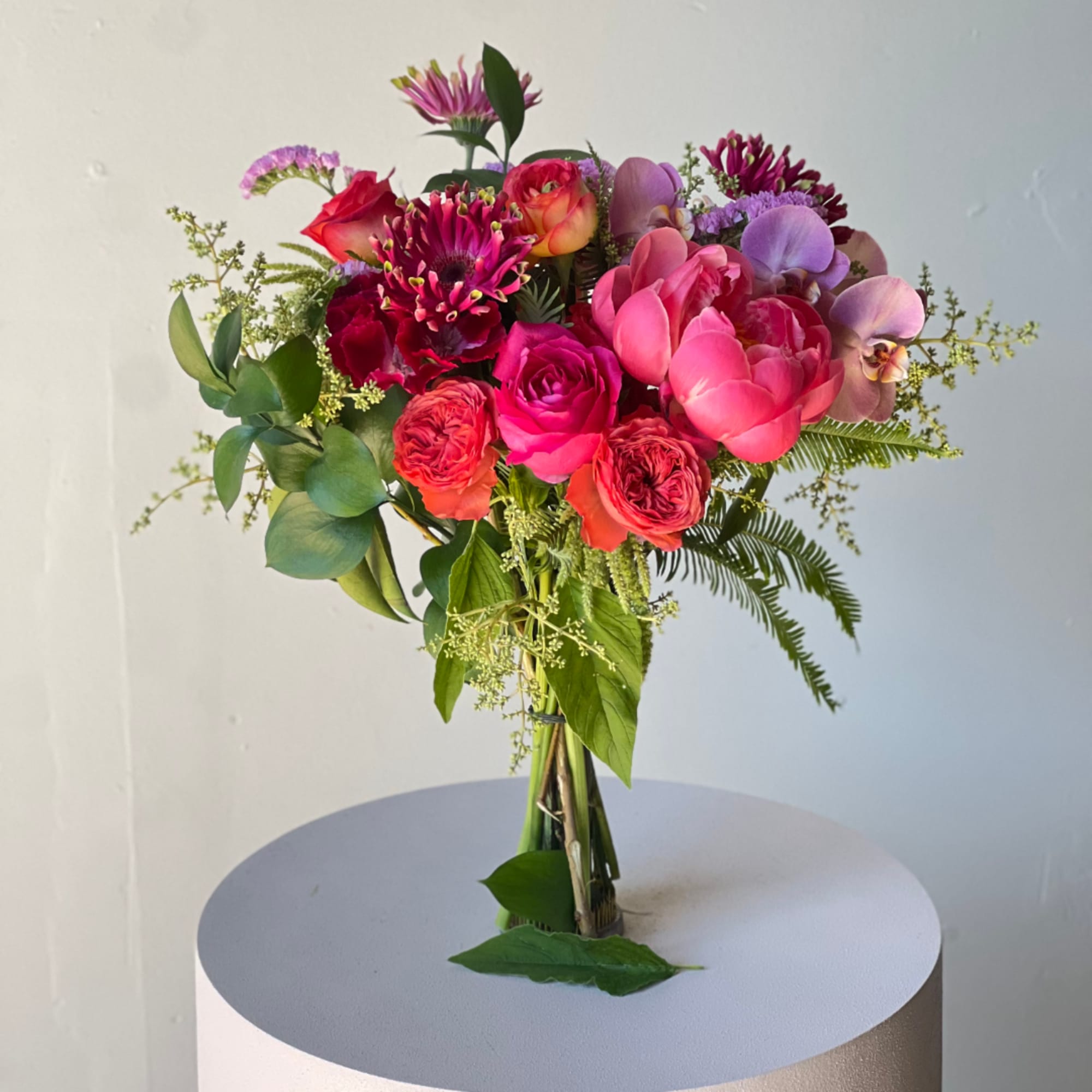 Mixed bouquet of pink, purple, and red flowers in a clear vase