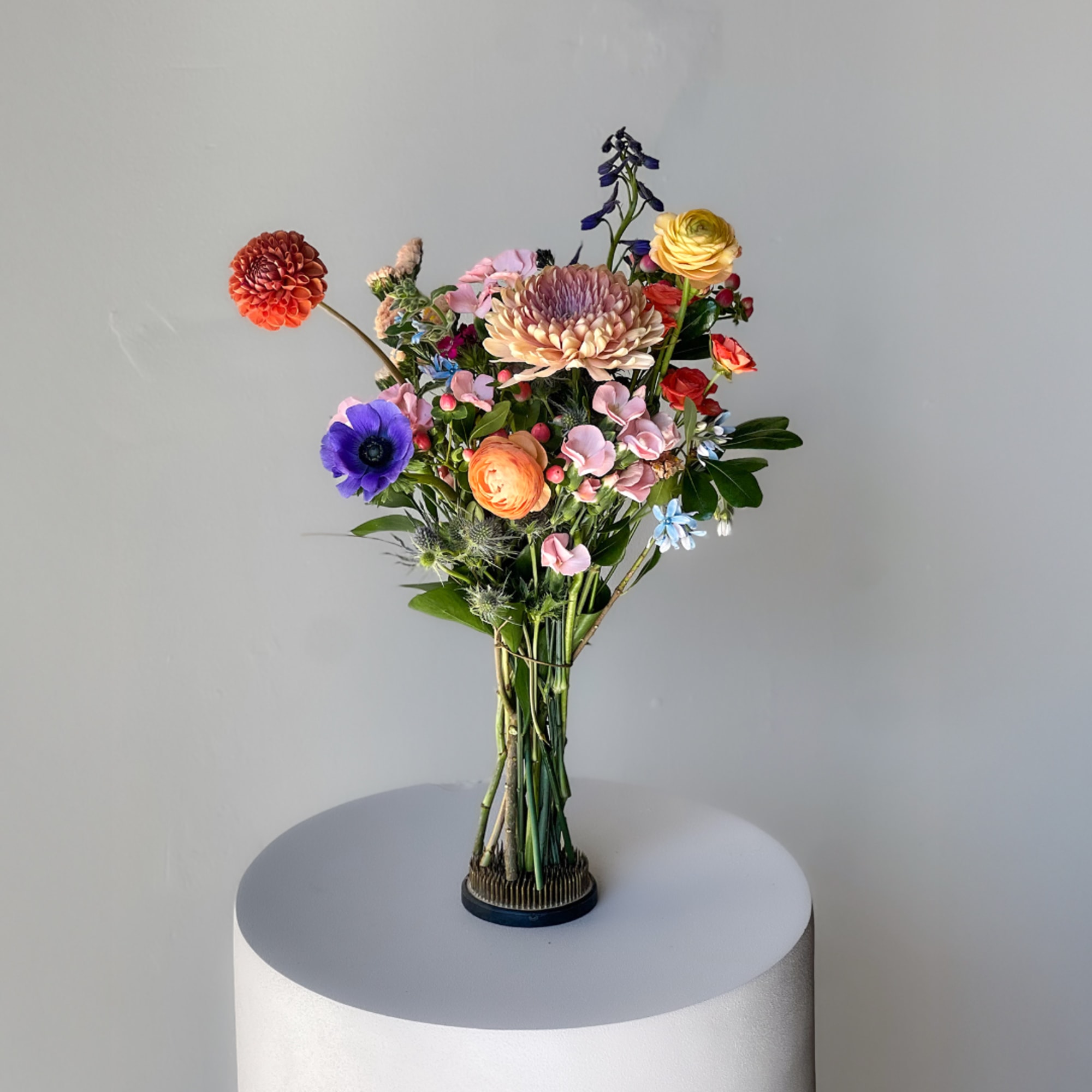 Mixed bouquet of colorful flowers in a small vase on a pedestal