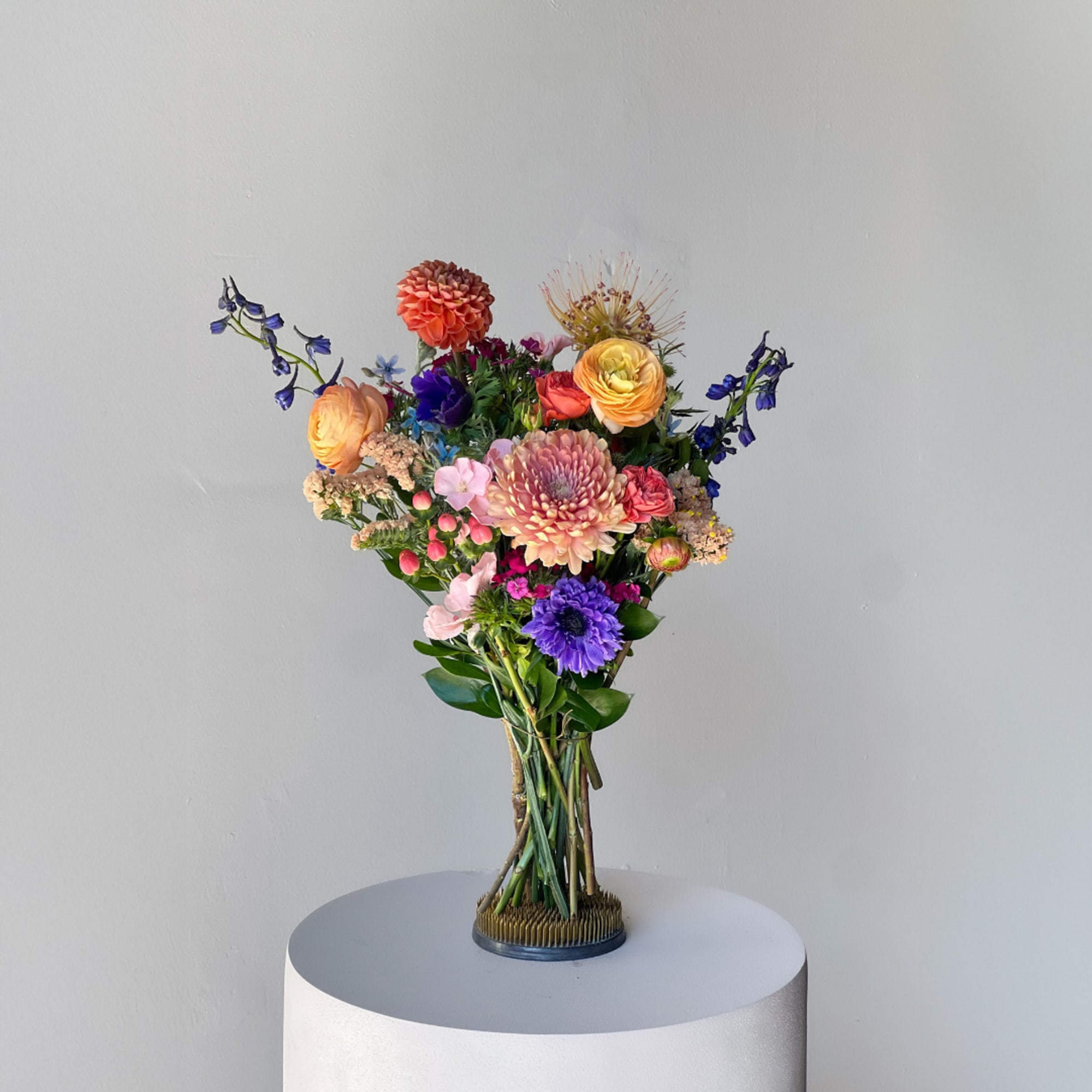 Tall mixed bouquet with orange, pink, purple, and yellow flowers in a vase