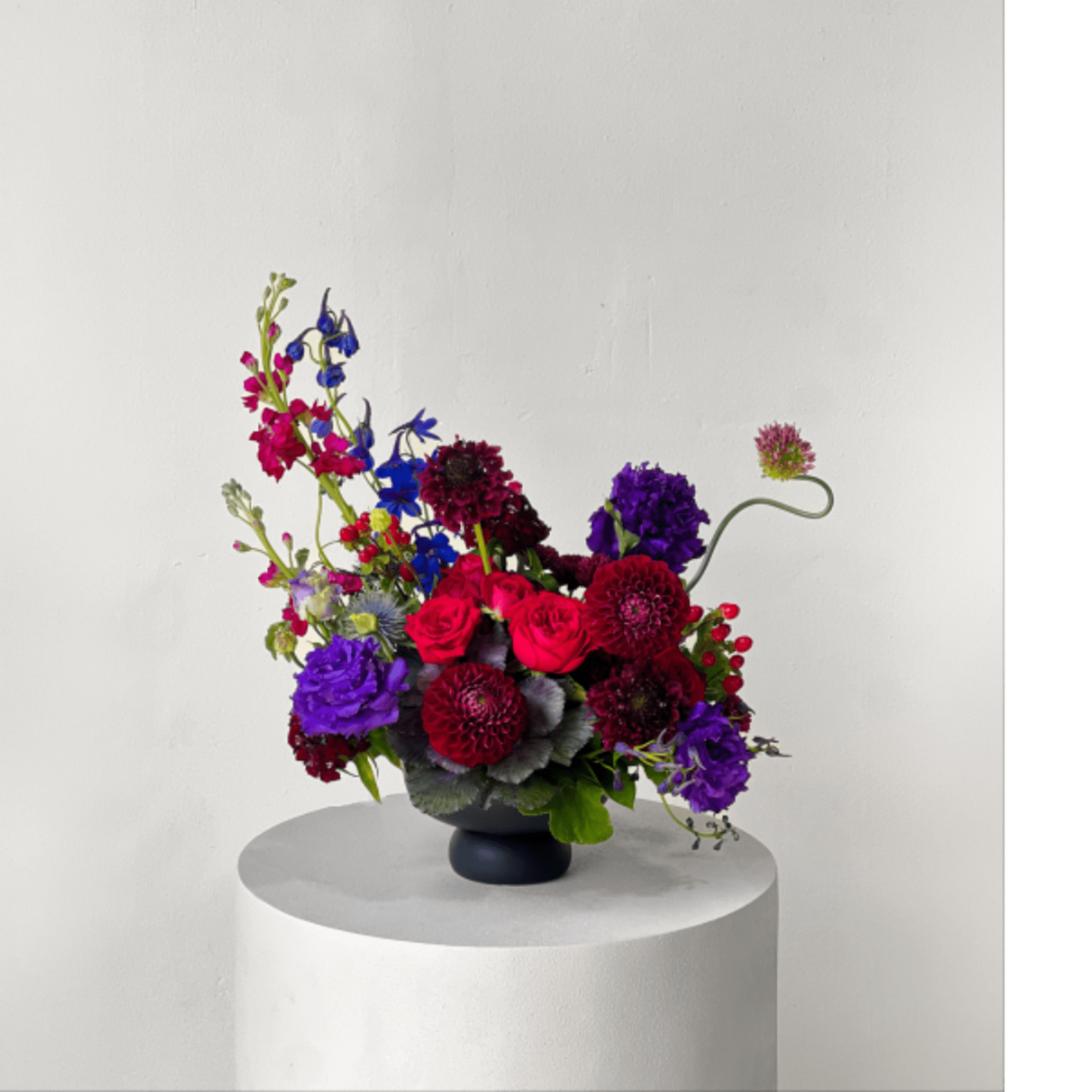 Colorful mixed flower arrangement in a dark vase on a pedestal