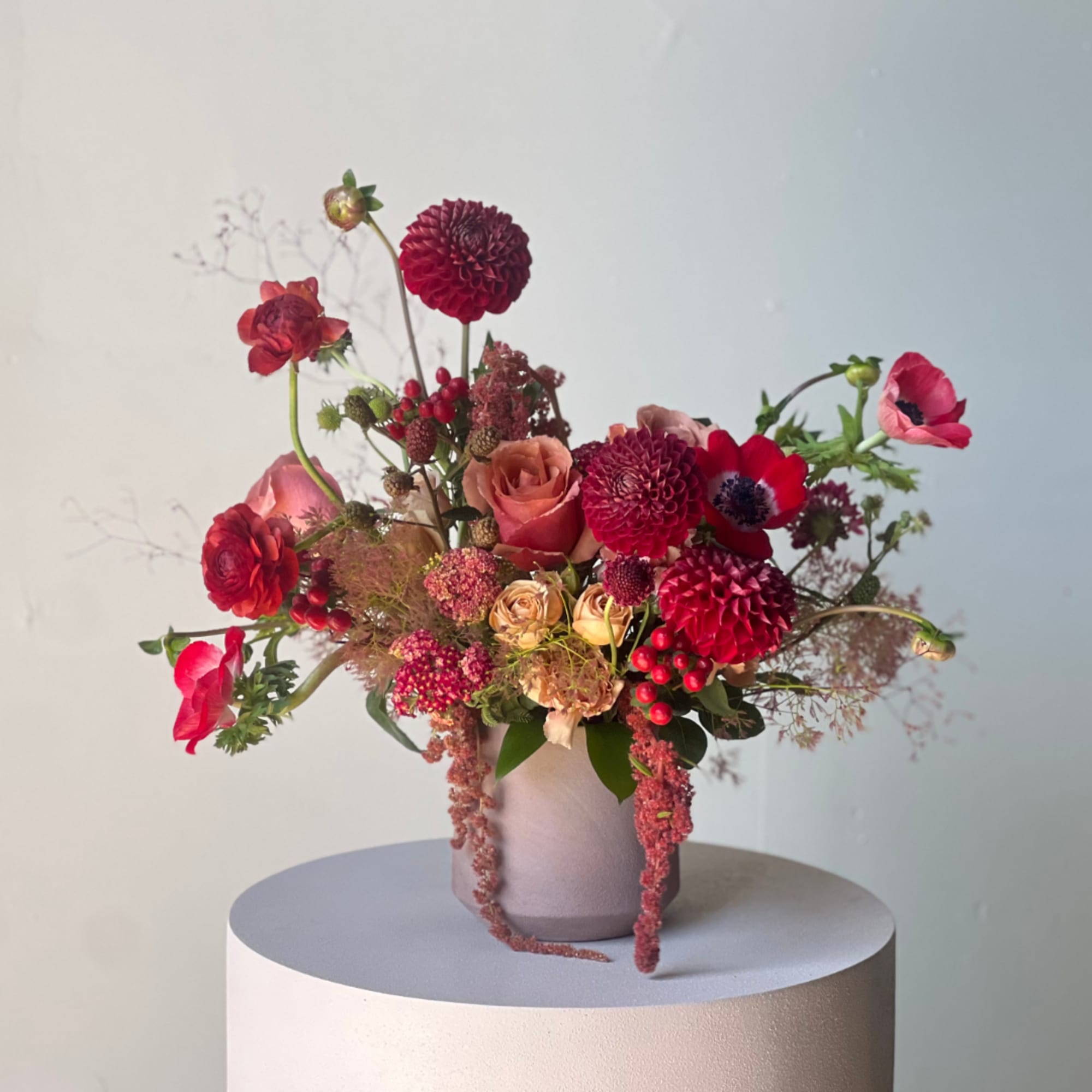 Red and pink mixed bouquet in a pale vase