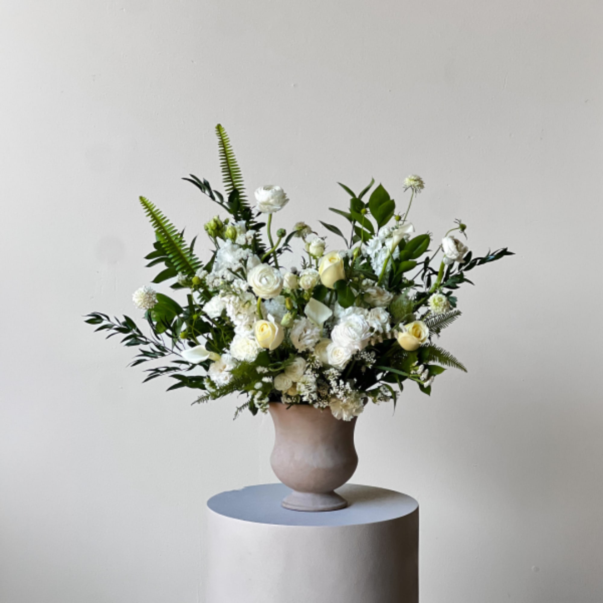 White and cream floral arrangement in a beige vase