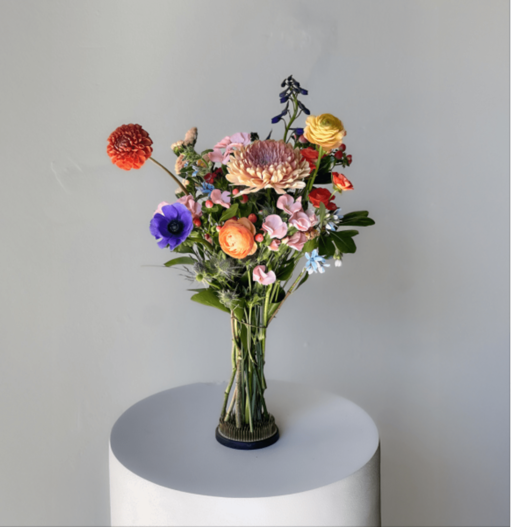 Colorful mixed bouquet in a clear glass vase on a pedestal