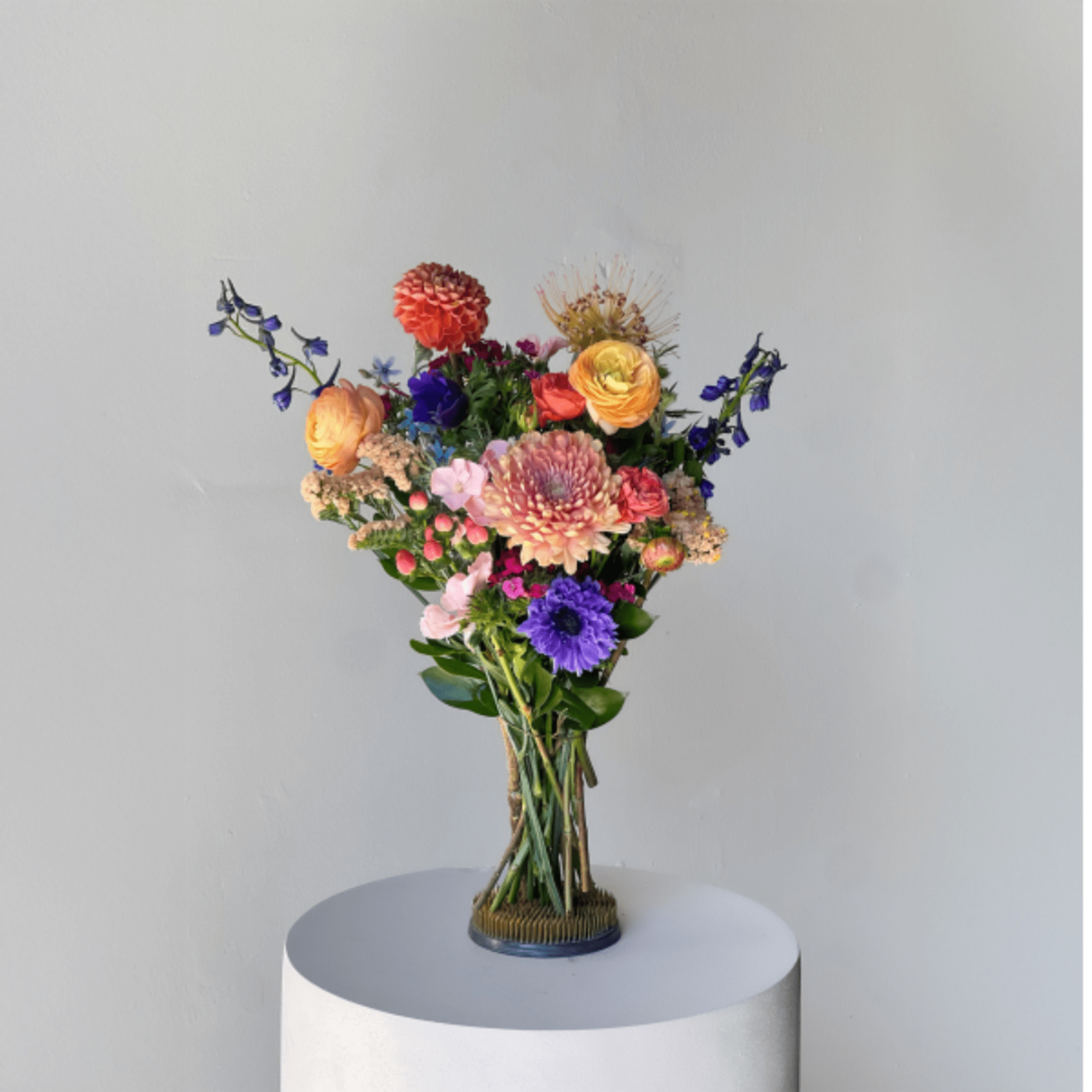 Colorful mixed bouquet in a clear vase on a pedestal