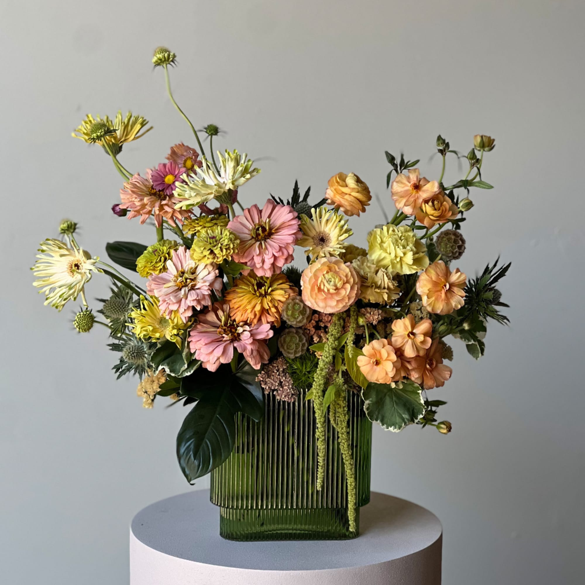 Mixed pastel flowers arranged in a green ribbed glass vase