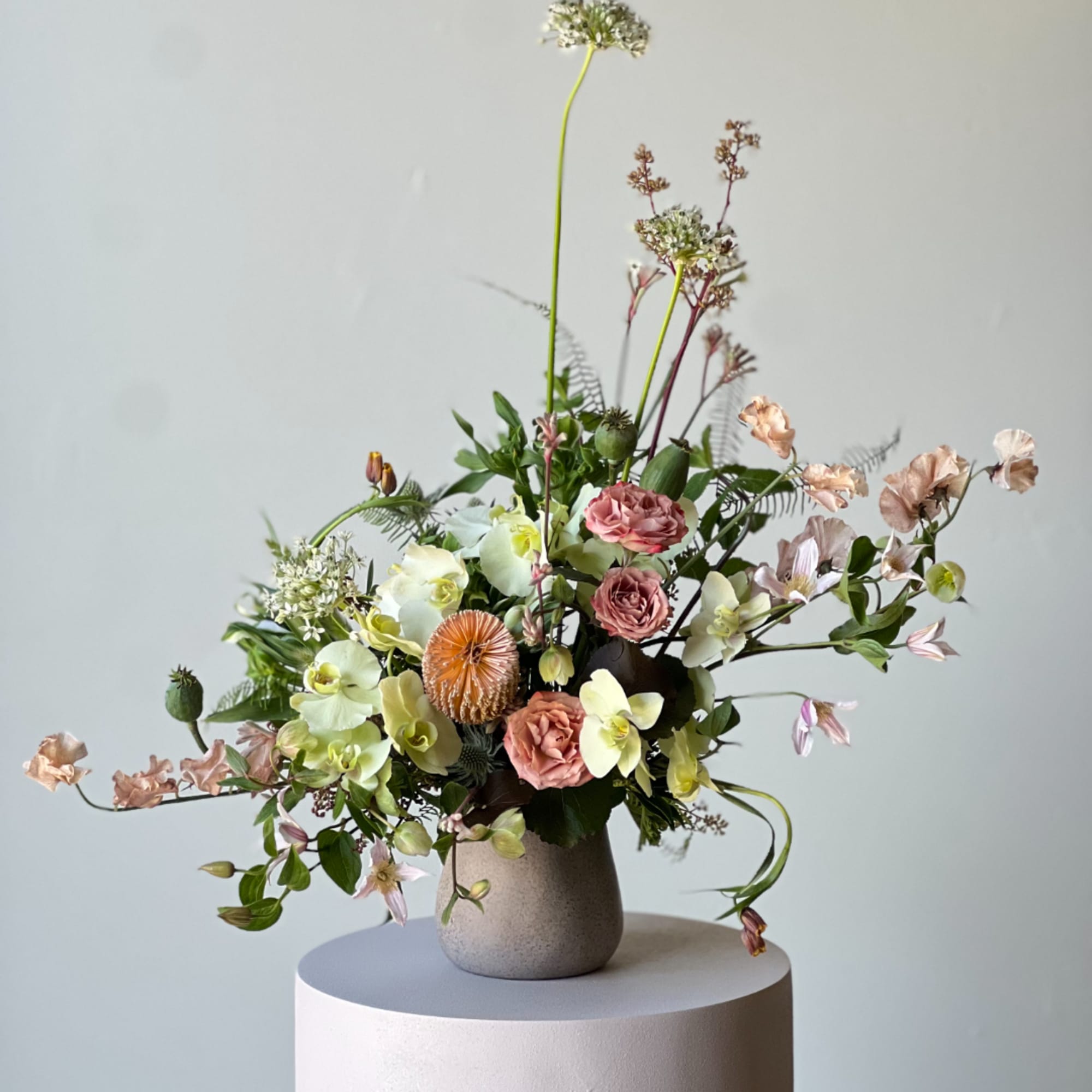 Mixed floral arrangement in a gray vase with pink and cream blooms