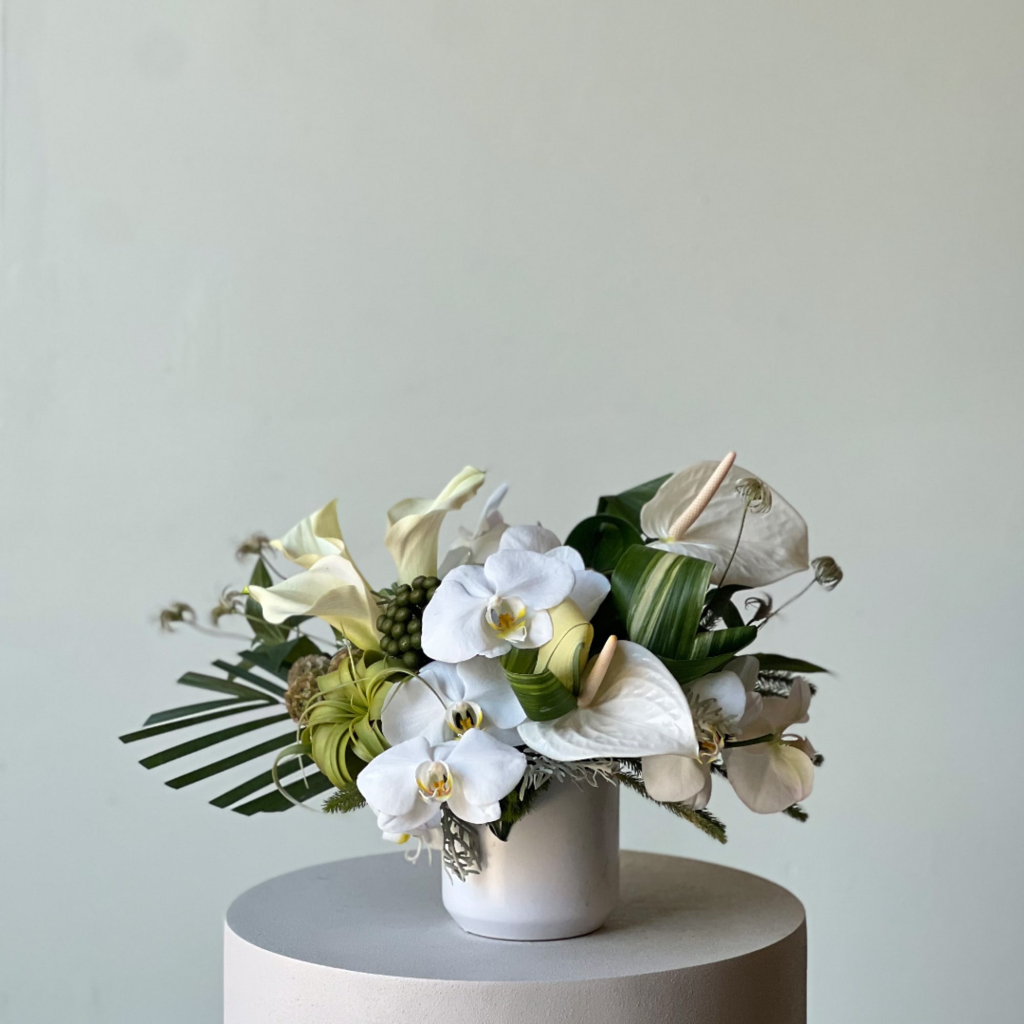 White orchid and calla lily arrangement in a white vase