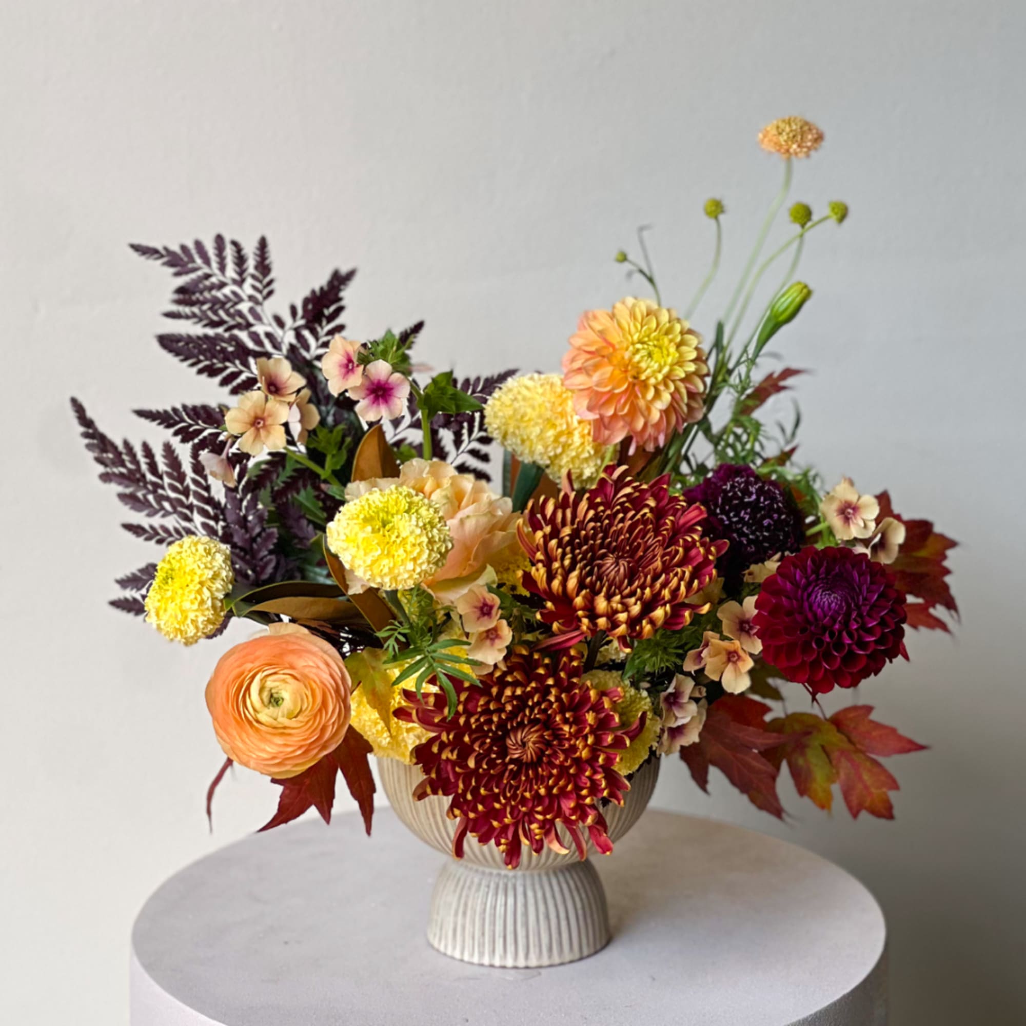 Mixed bouquet in a ribbed pedestal vase with chrysanthemums and ranunculus