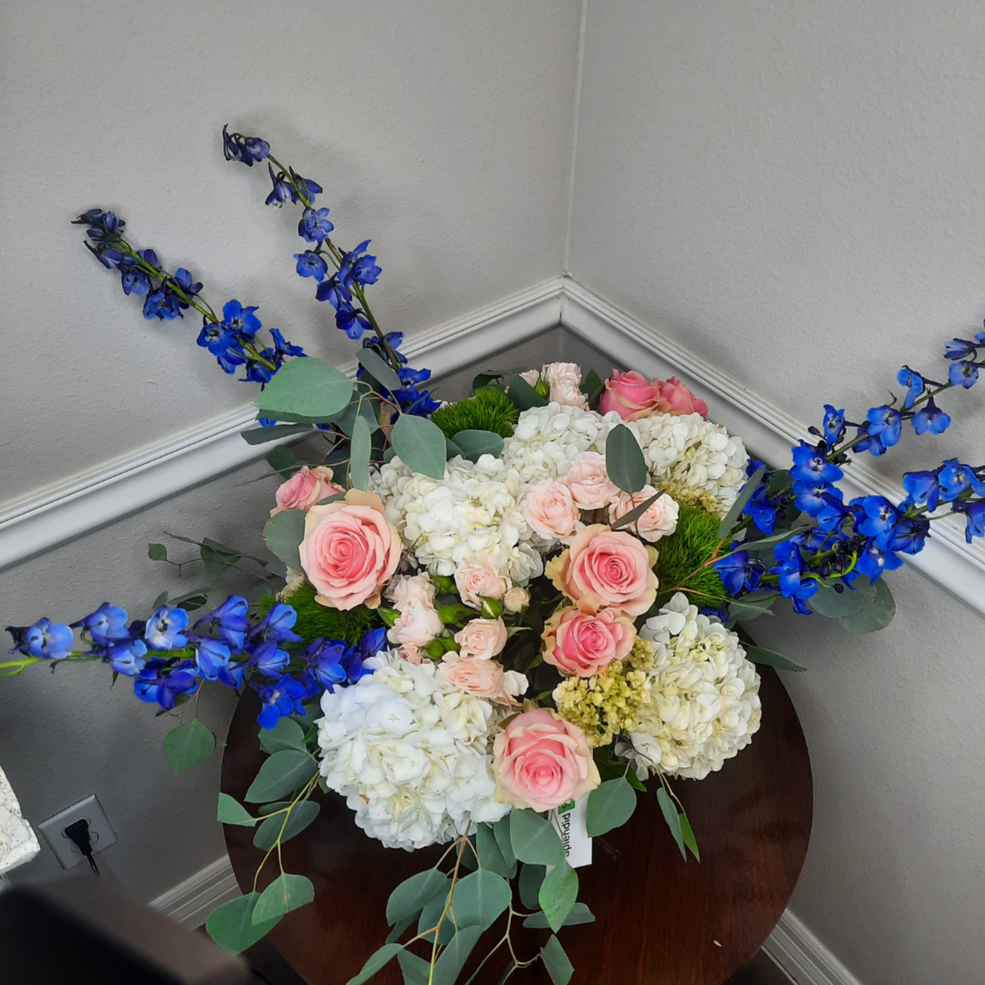 Pink roses and white hydrangeas with blue delphinium in a low arrangement