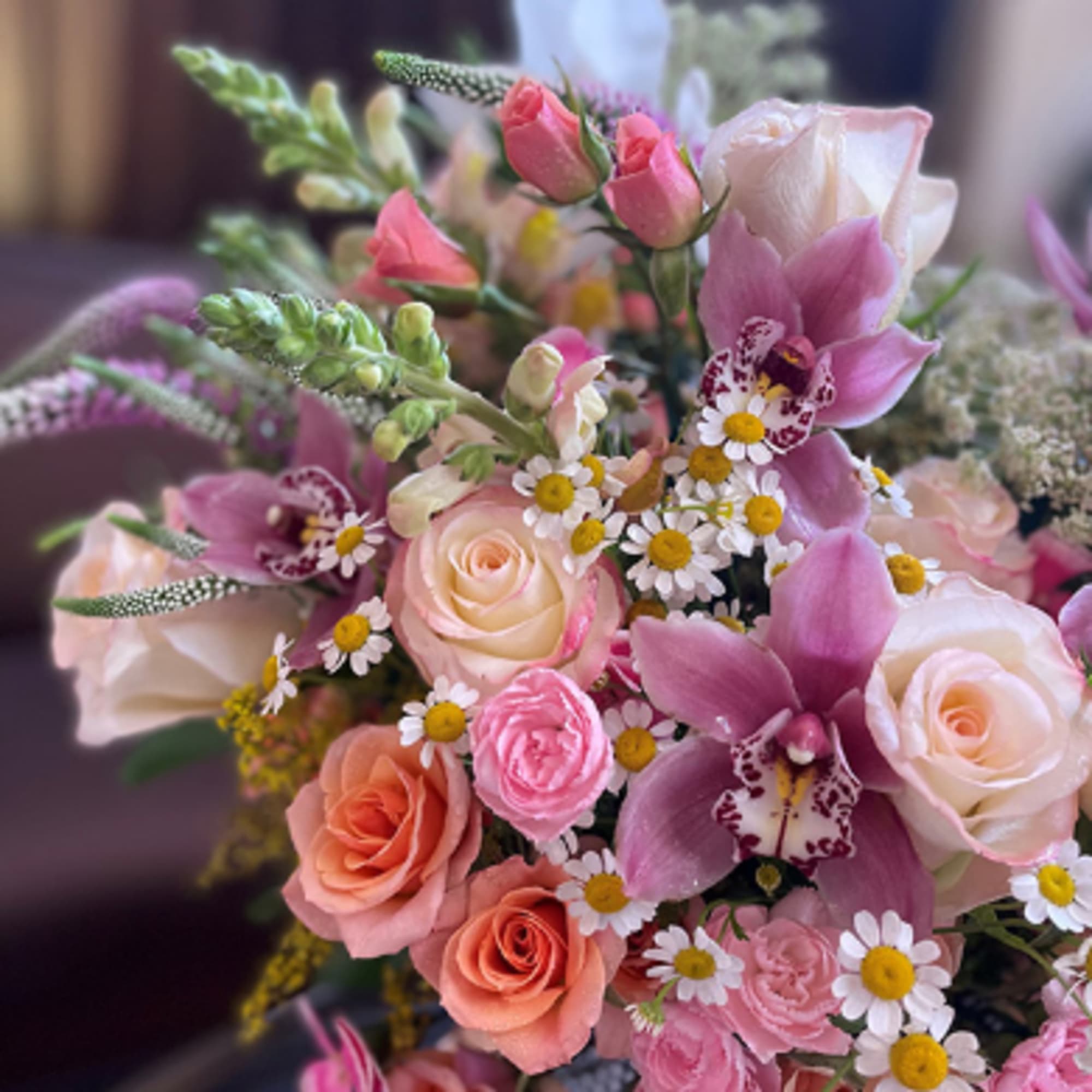 Bouquet of pink and peach roses with purple orchids and small white daisies