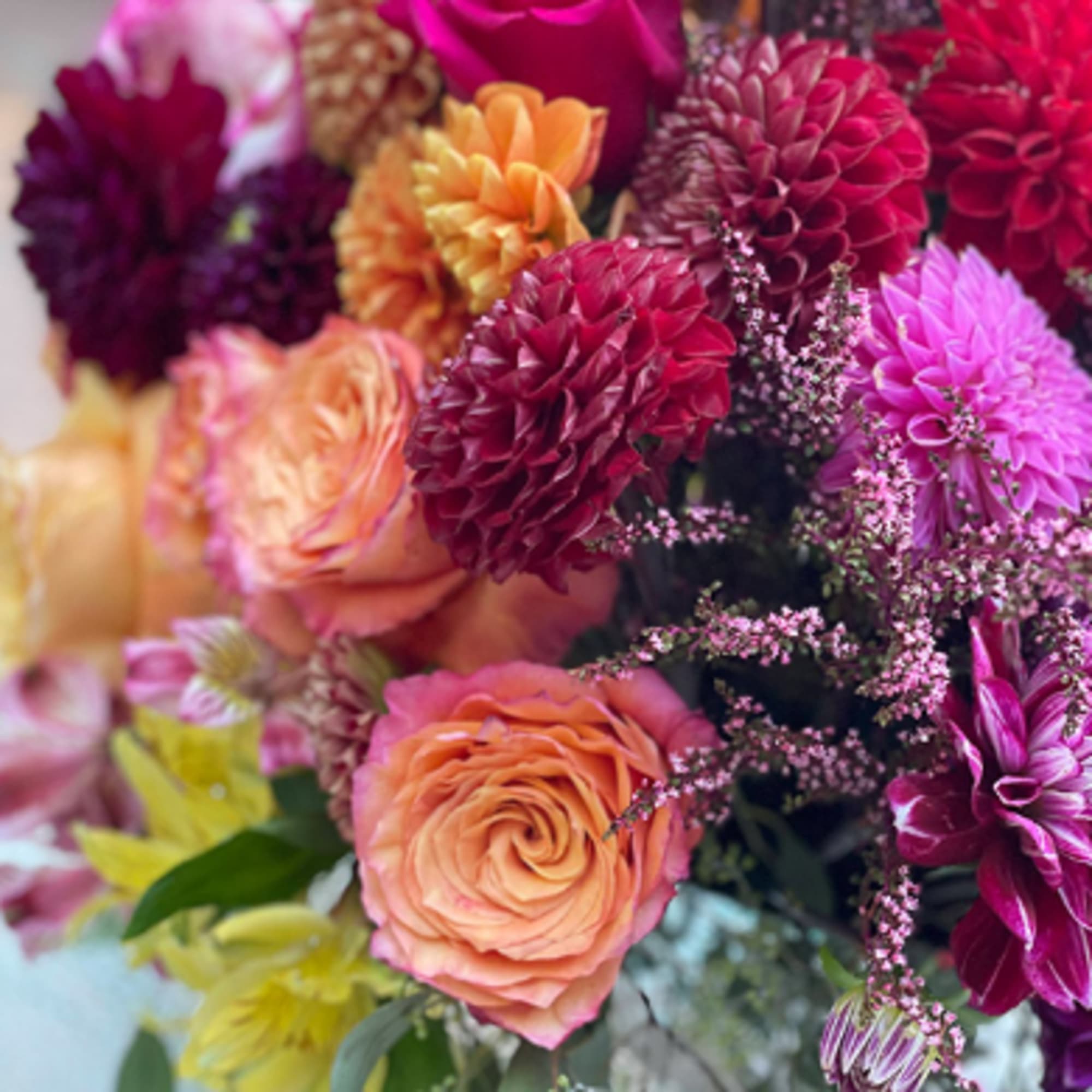 Close-up bouquet of orange roses and magenta dahlias with small pink filler flowers