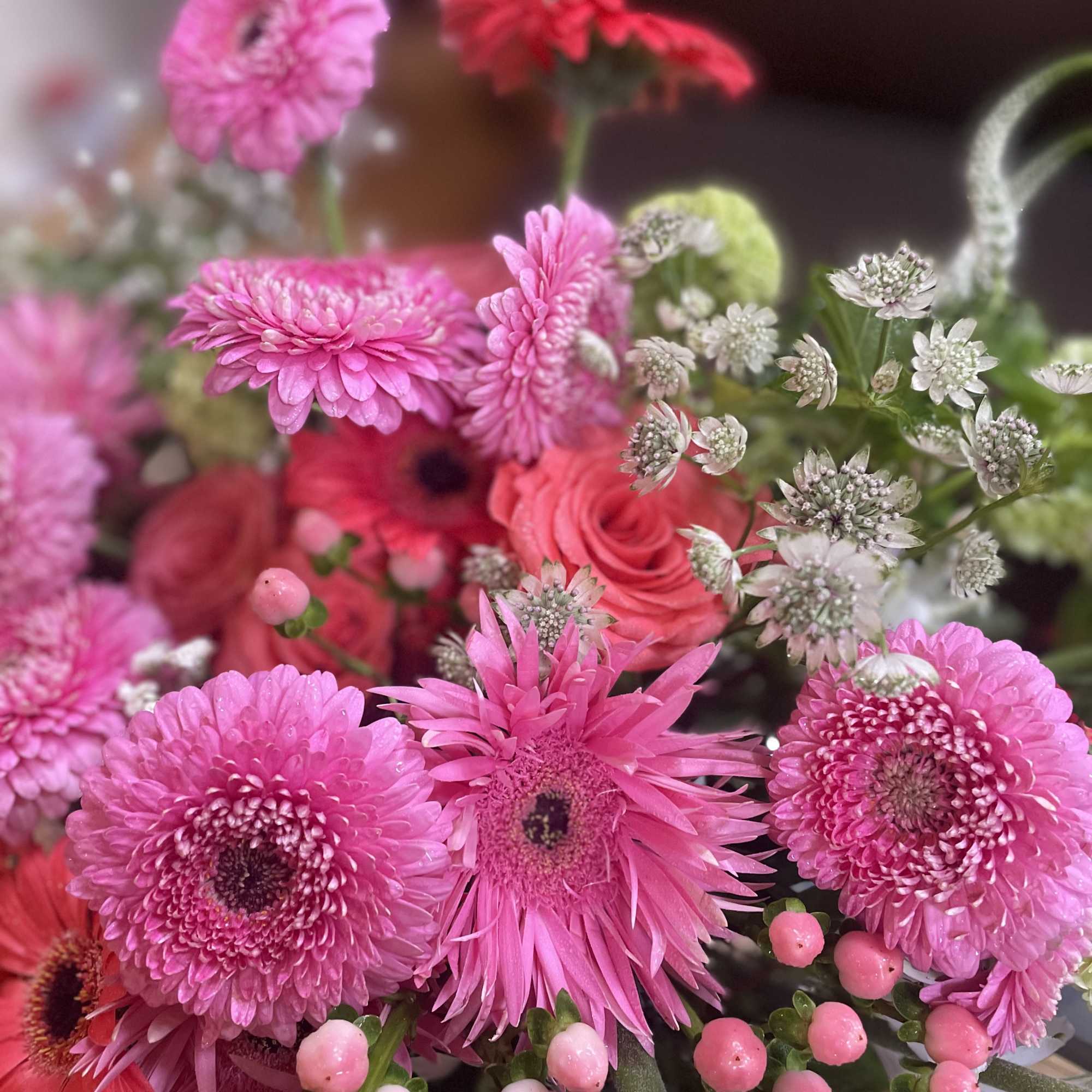 Pink and red mixed bouquet with gerbera daisies, roses, and small white filler flowers