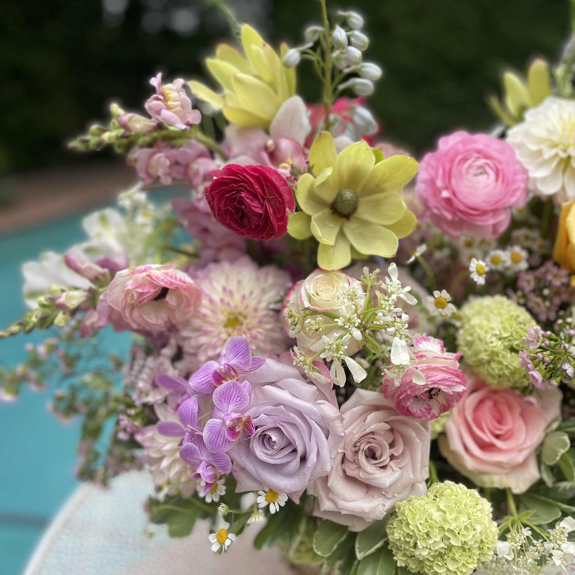 Pastel bouquet with roses, ranunculus, orchids, and small daisies