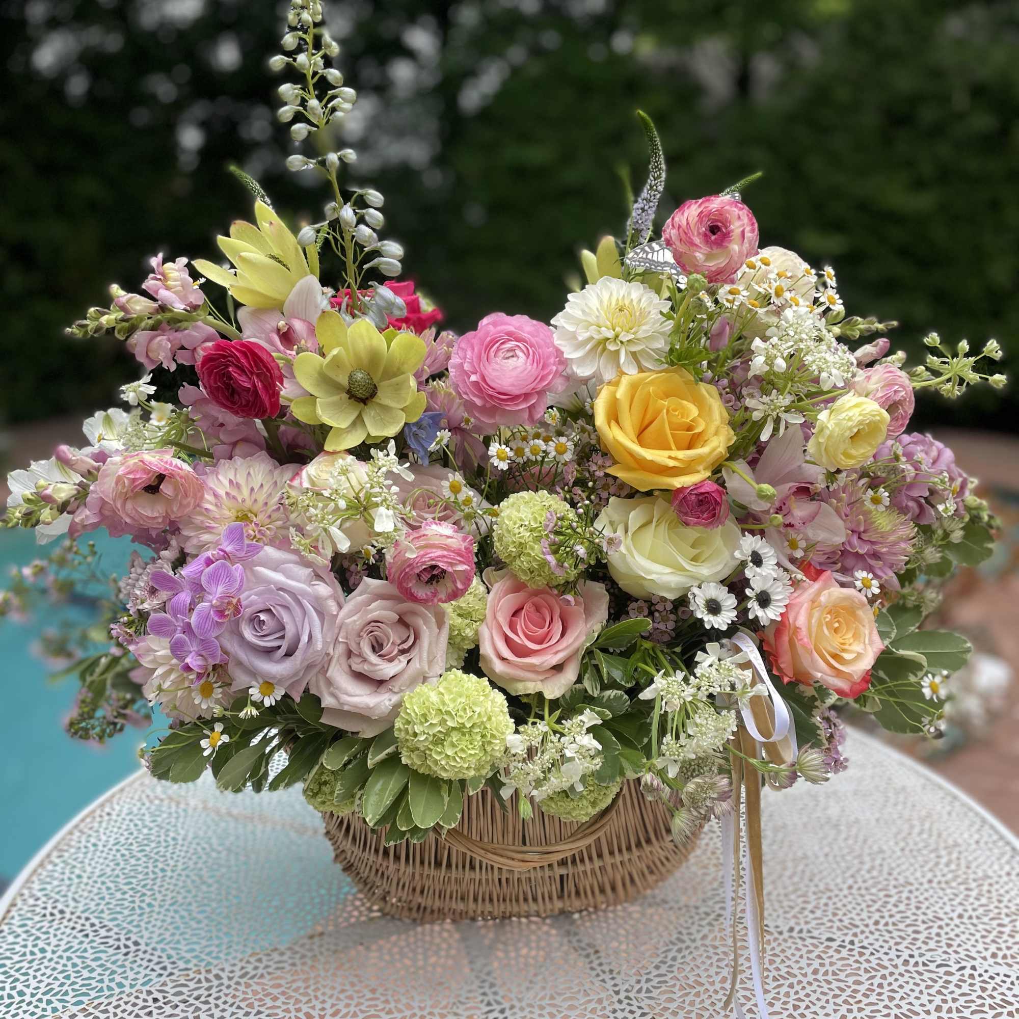 Mixed pastel bouquet in a wicker basket with roses and daisies