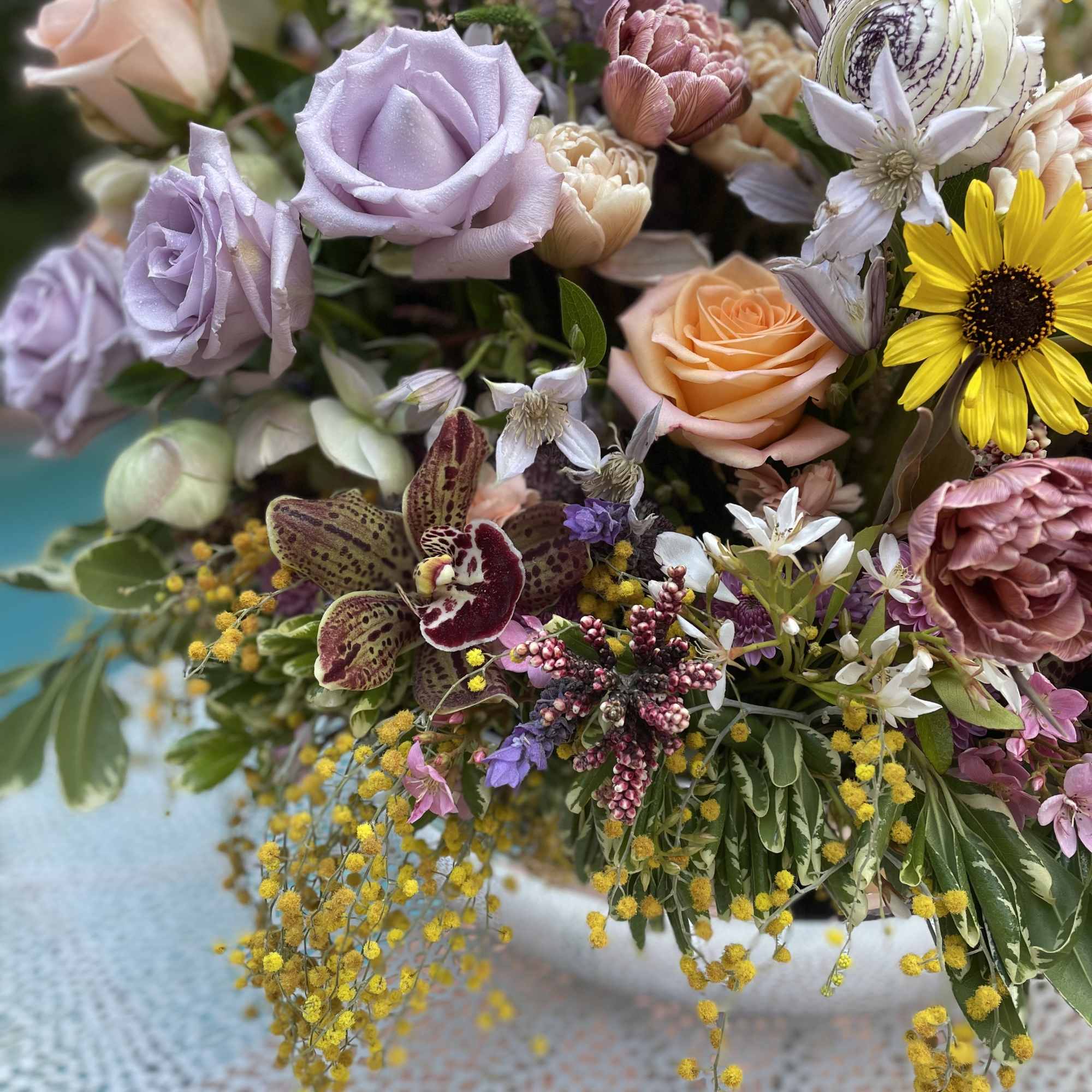 Mixed bouquet with lavender and peach roses, yellow daisies, and orchids