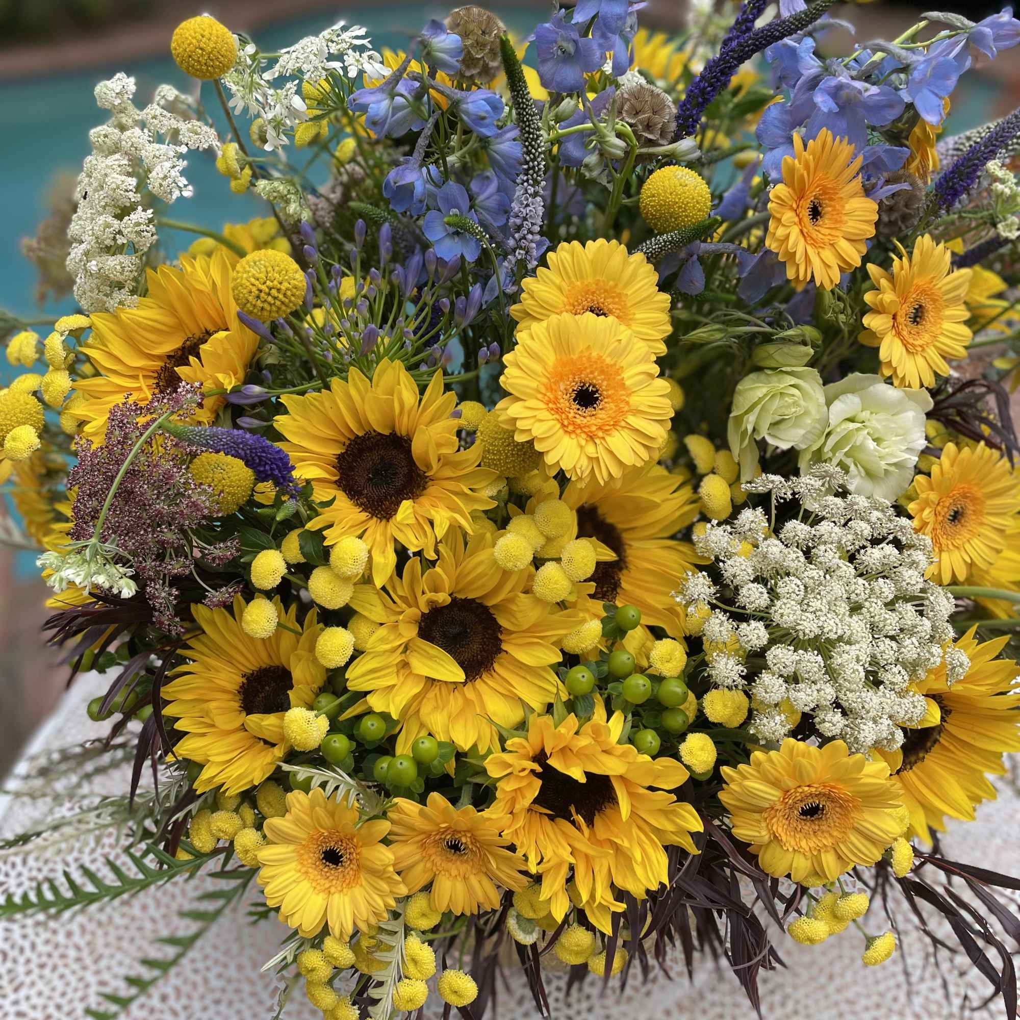 Bouquet of yellow sunflowers and blue flowers with white filler blooms