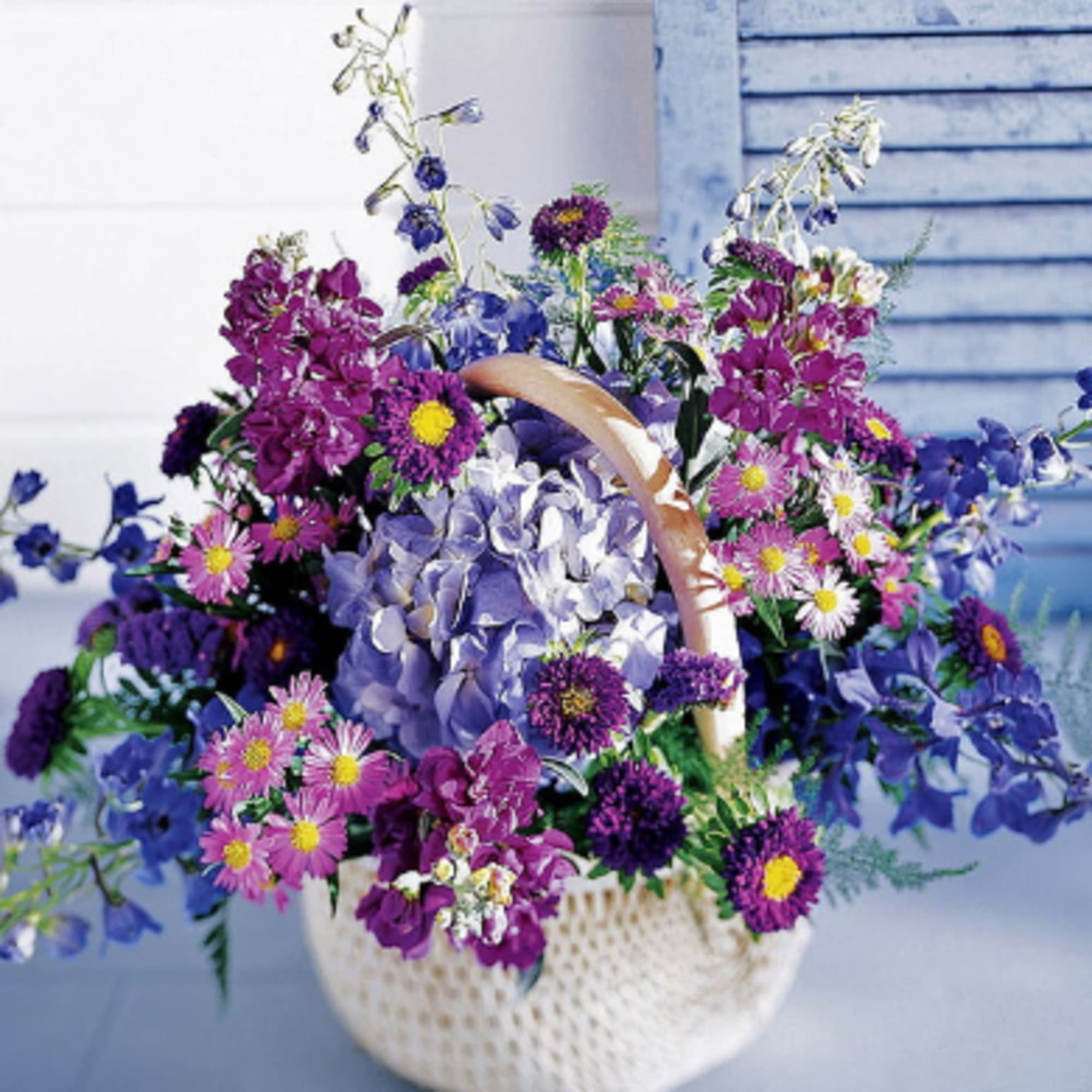 Basket of purple and blue flowers with a pale blue hydrangea center