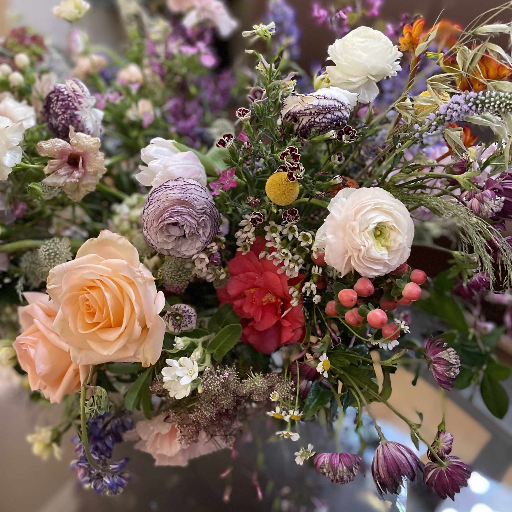 Mixed bouquet with peach roses, white ranunculus, and purple blooms