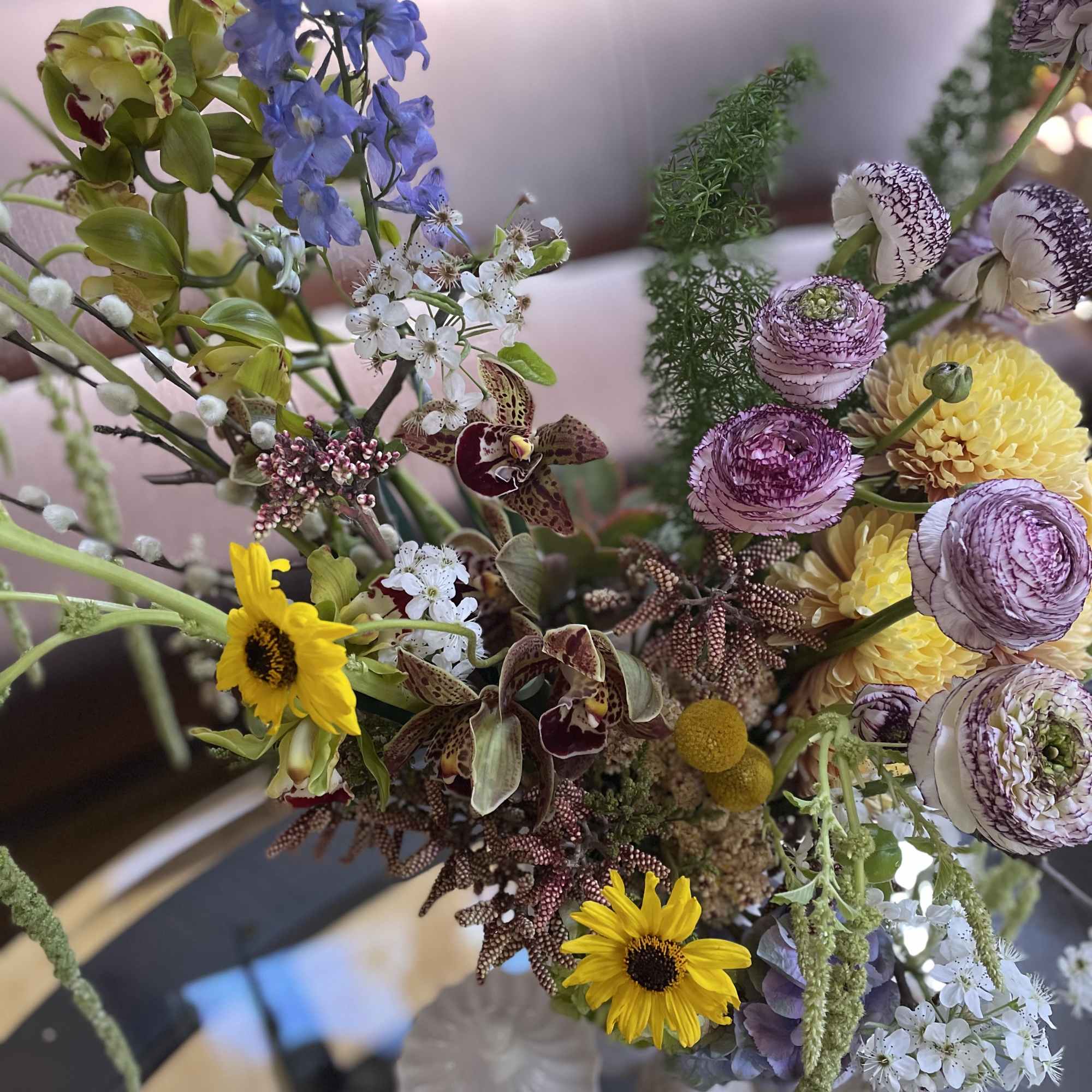Mixed bouquet with orchids, sunflowers, and purple blooms in a vase