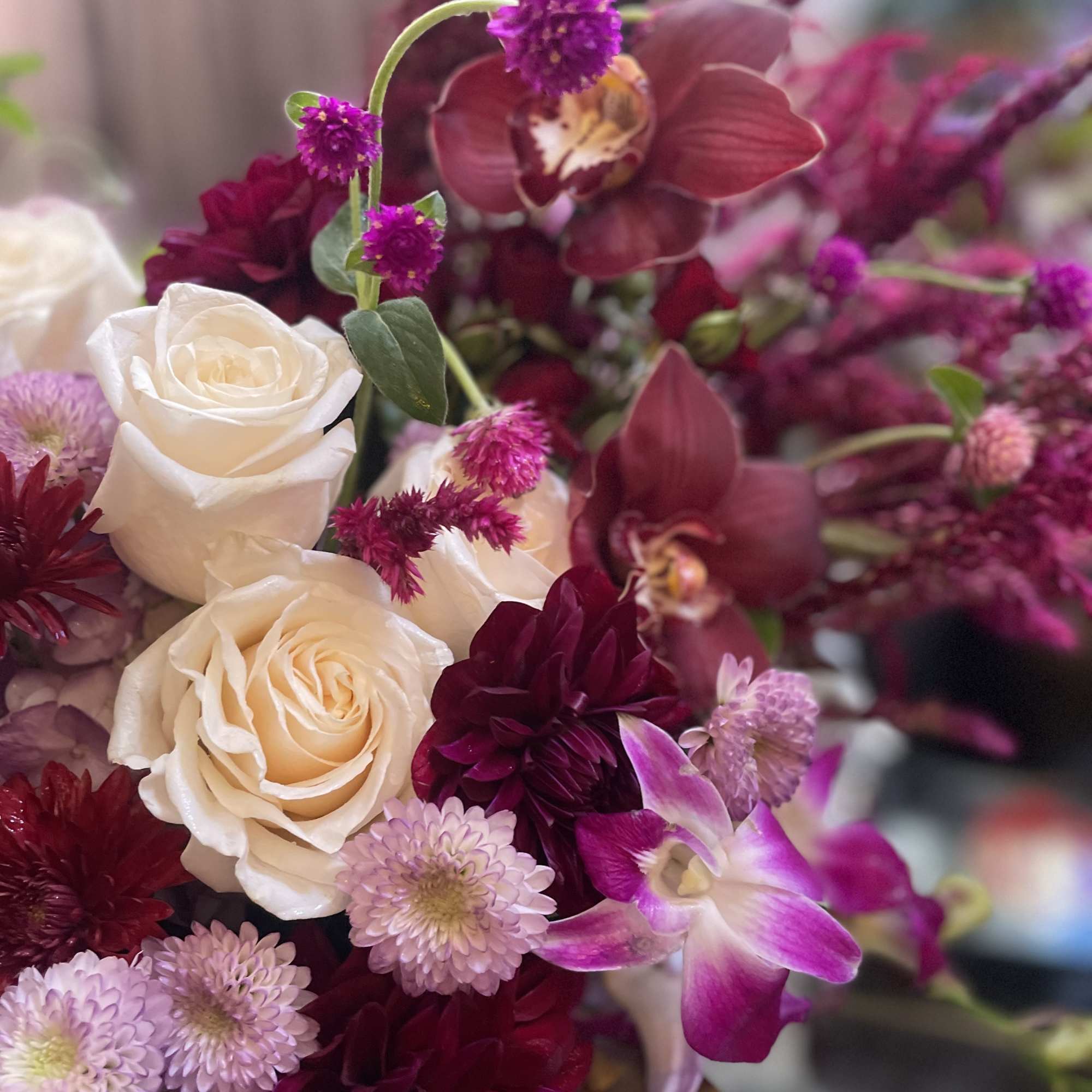 Bouquet of cream roses and magenta orchids with small purple blooms