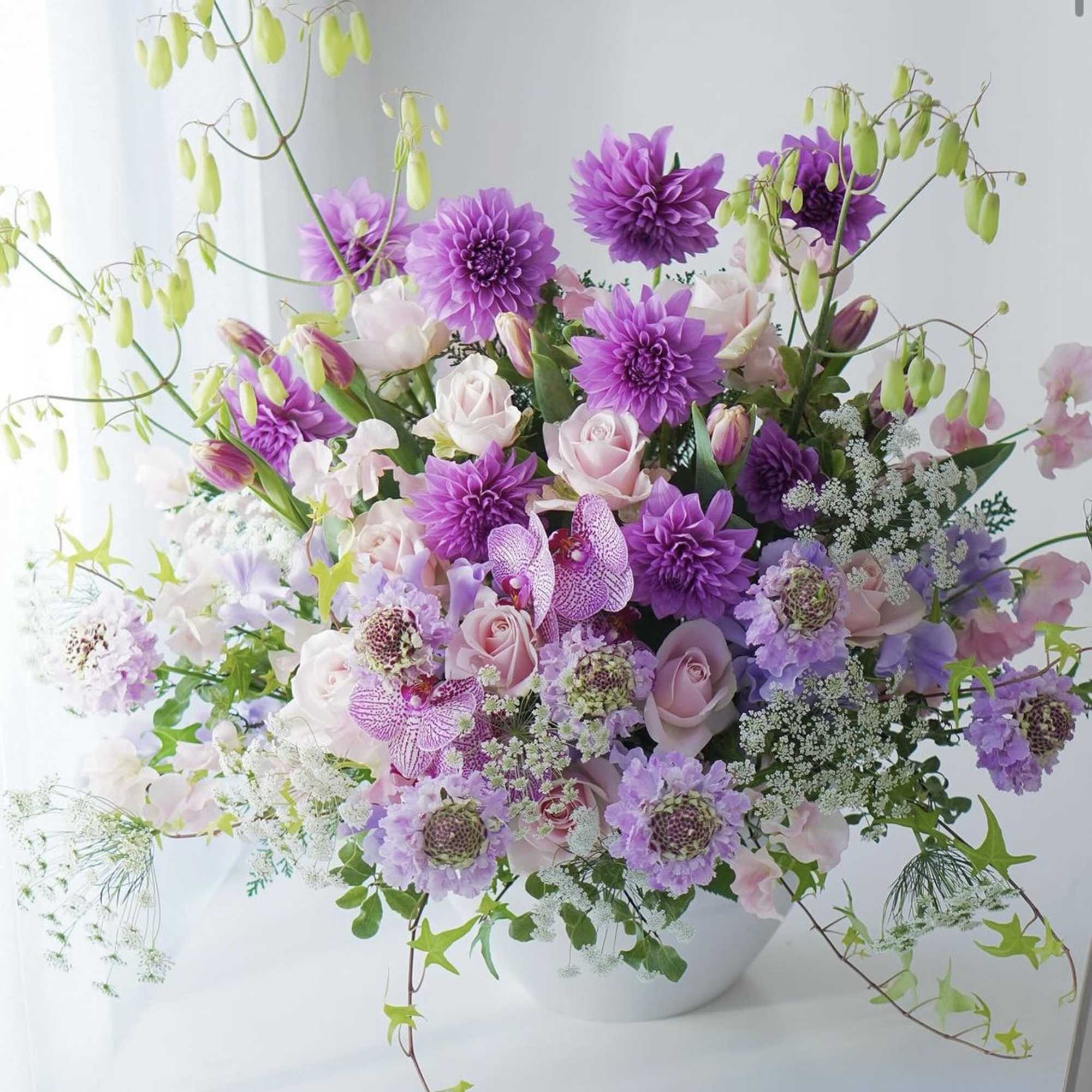 Lavender and pink floral arrangement in a white bowl vase