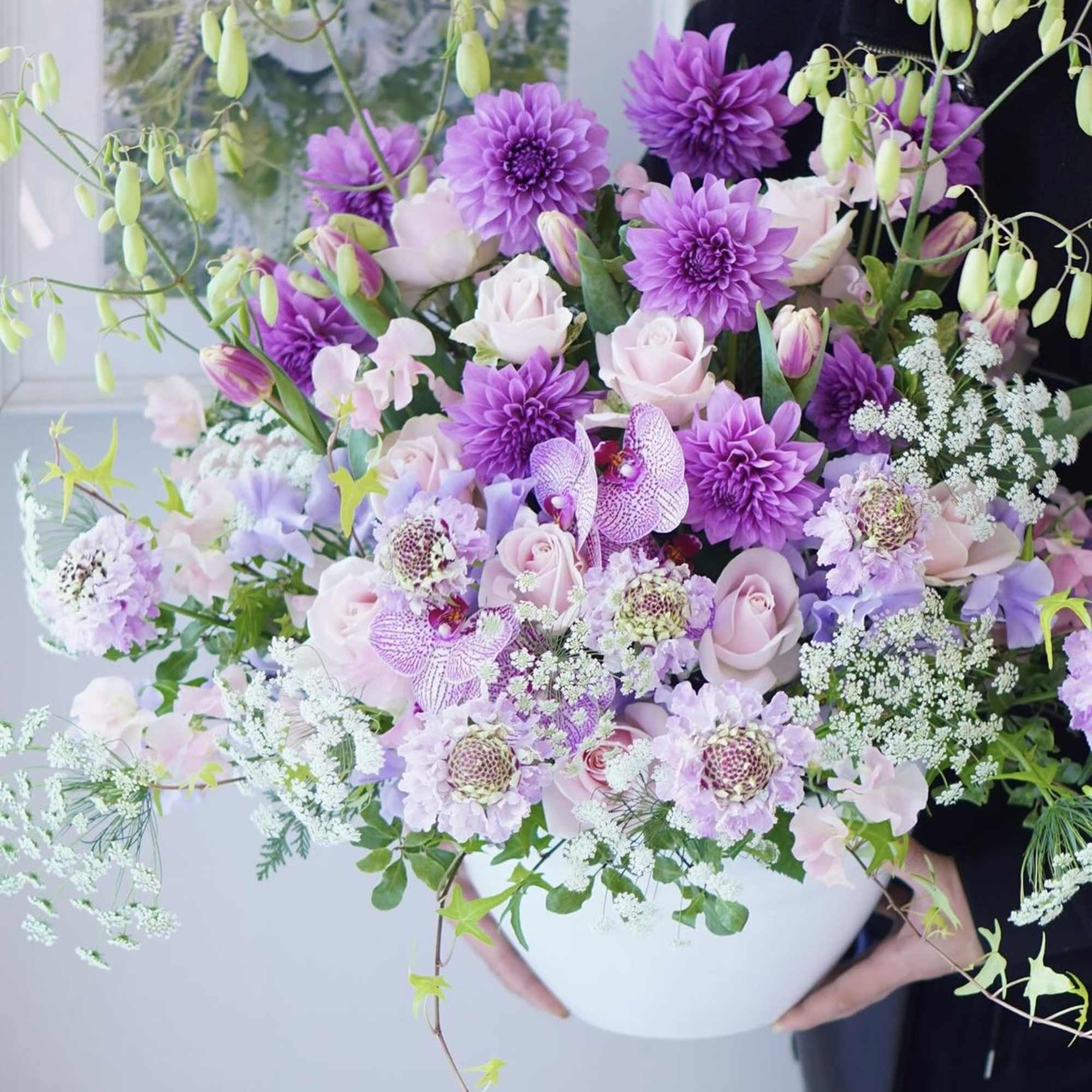 Large bouquet of purple and pale pink flowers in a white vase