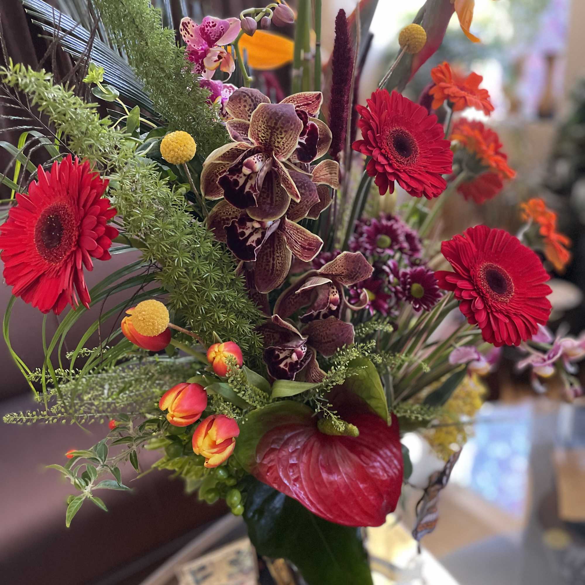 Tropical bouquet with red gerberas, orchids, and orange tulips