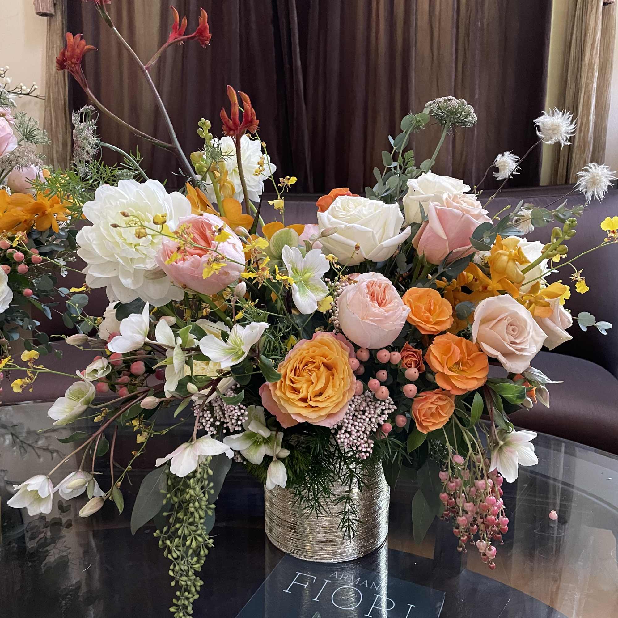 Large mixed bouquet of peach, white, and orange flowers in a metallic vase