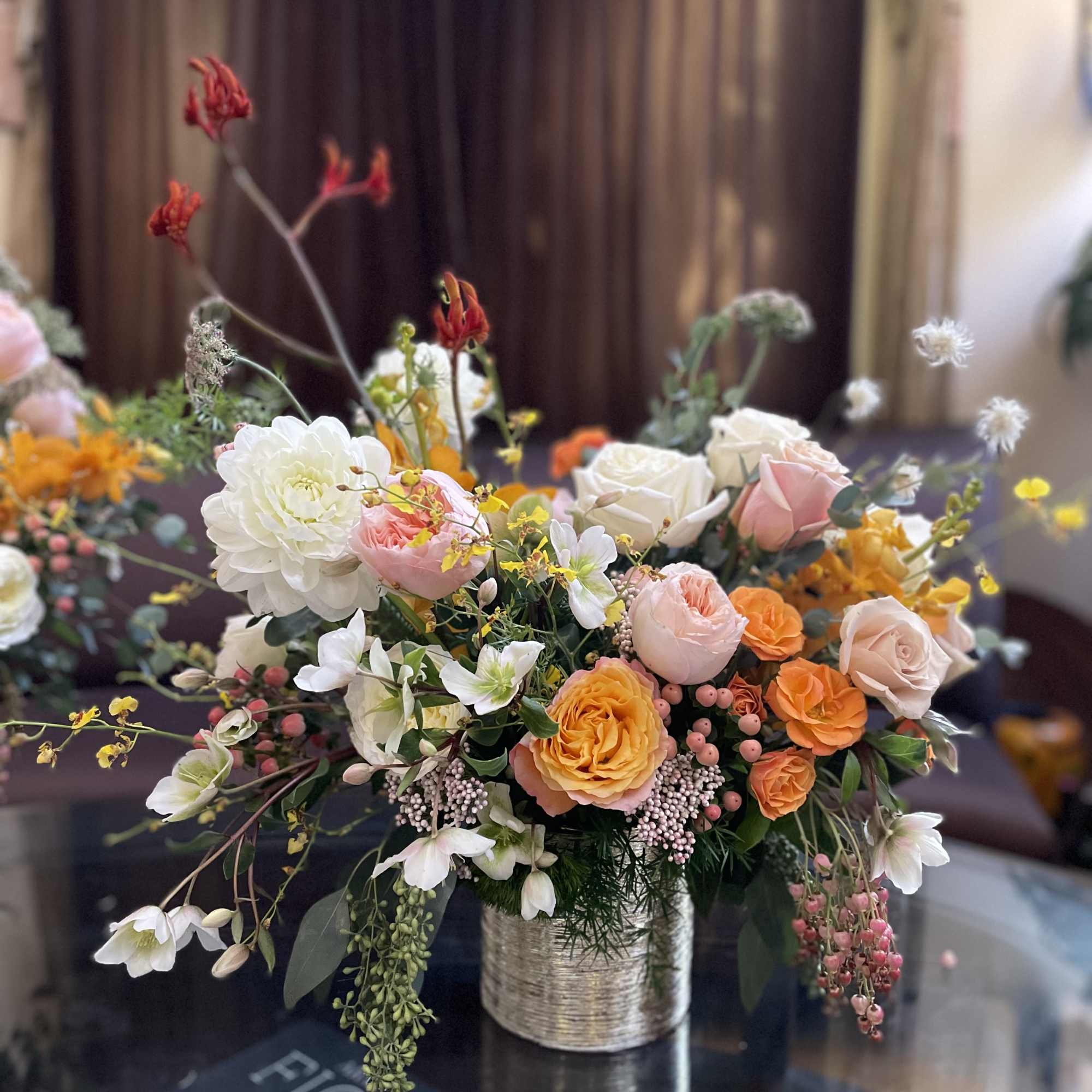 Mixed bouquet of peach, pink, white, and orange flowers in a wrapped vase