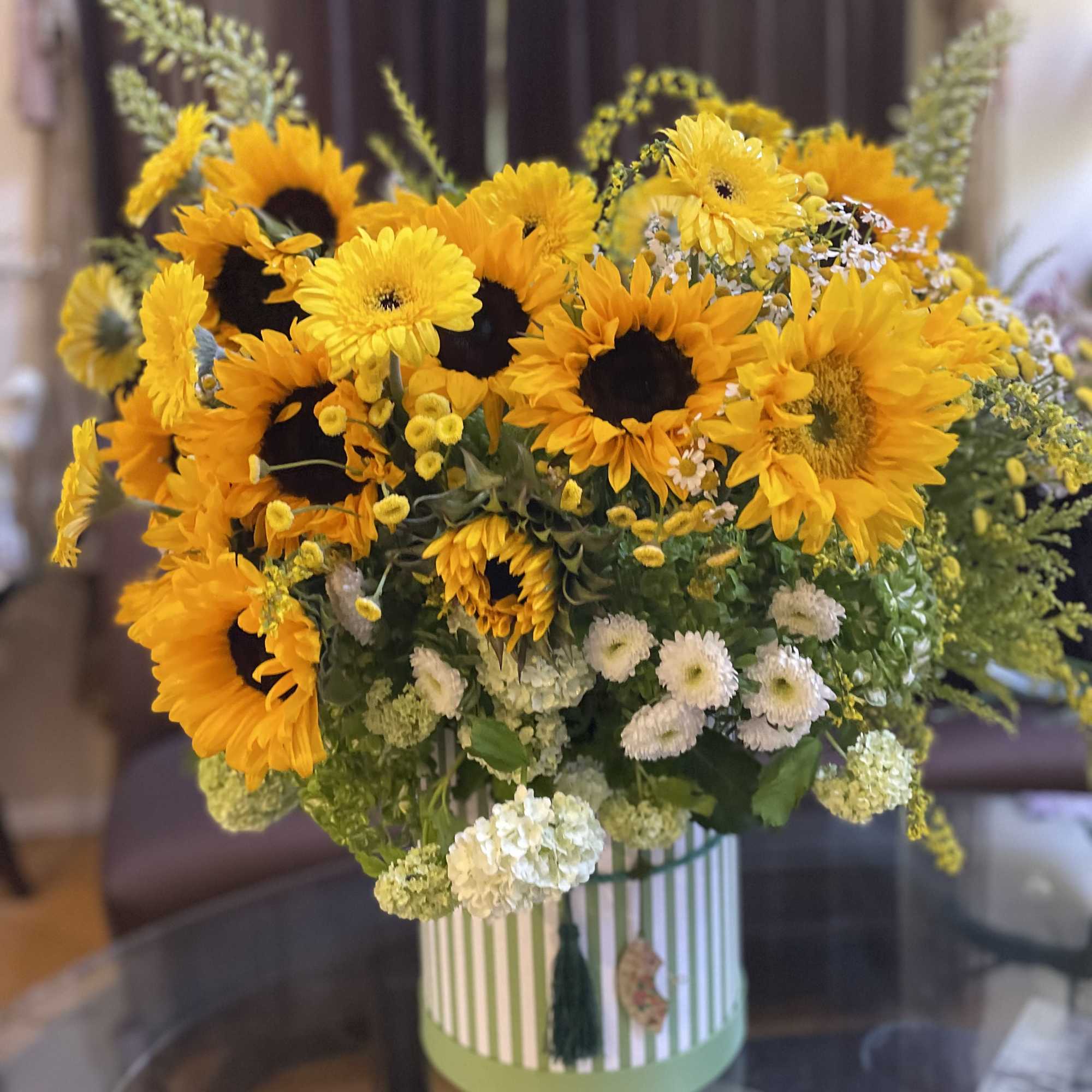 Sunflower bouquet in a striped round box with white accent flowers