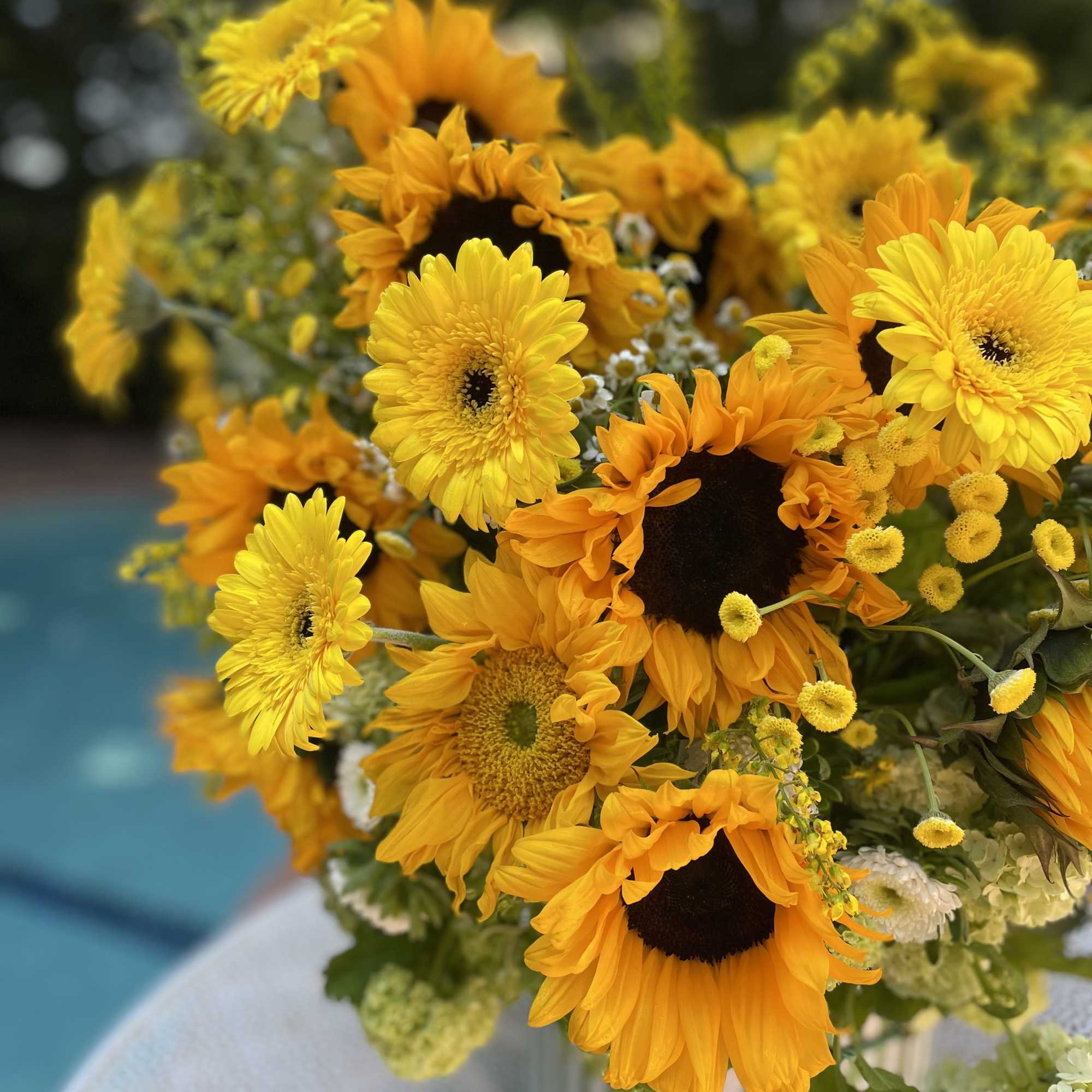 Bouquet of yellow sunflowers and daisies in a striped vase