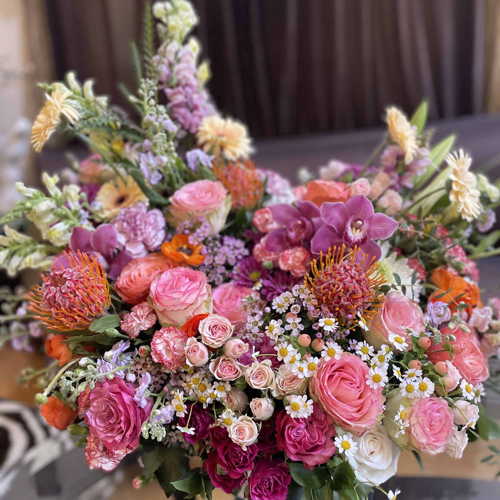 Large bouquet of pink and orange flowers with orchids and roses