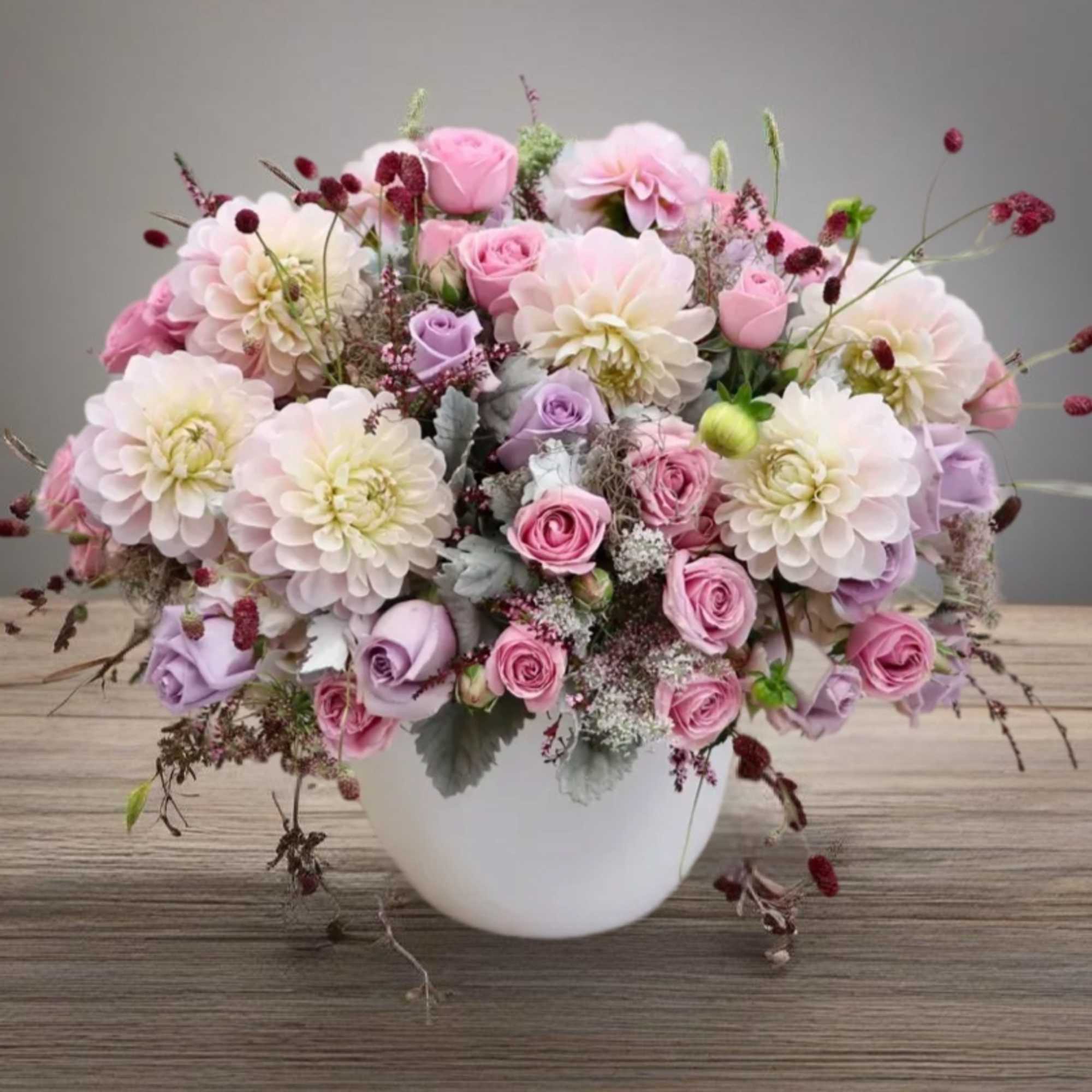 Pink and lavender roses with pale dahlias in a white vase, photo 2 of 6
