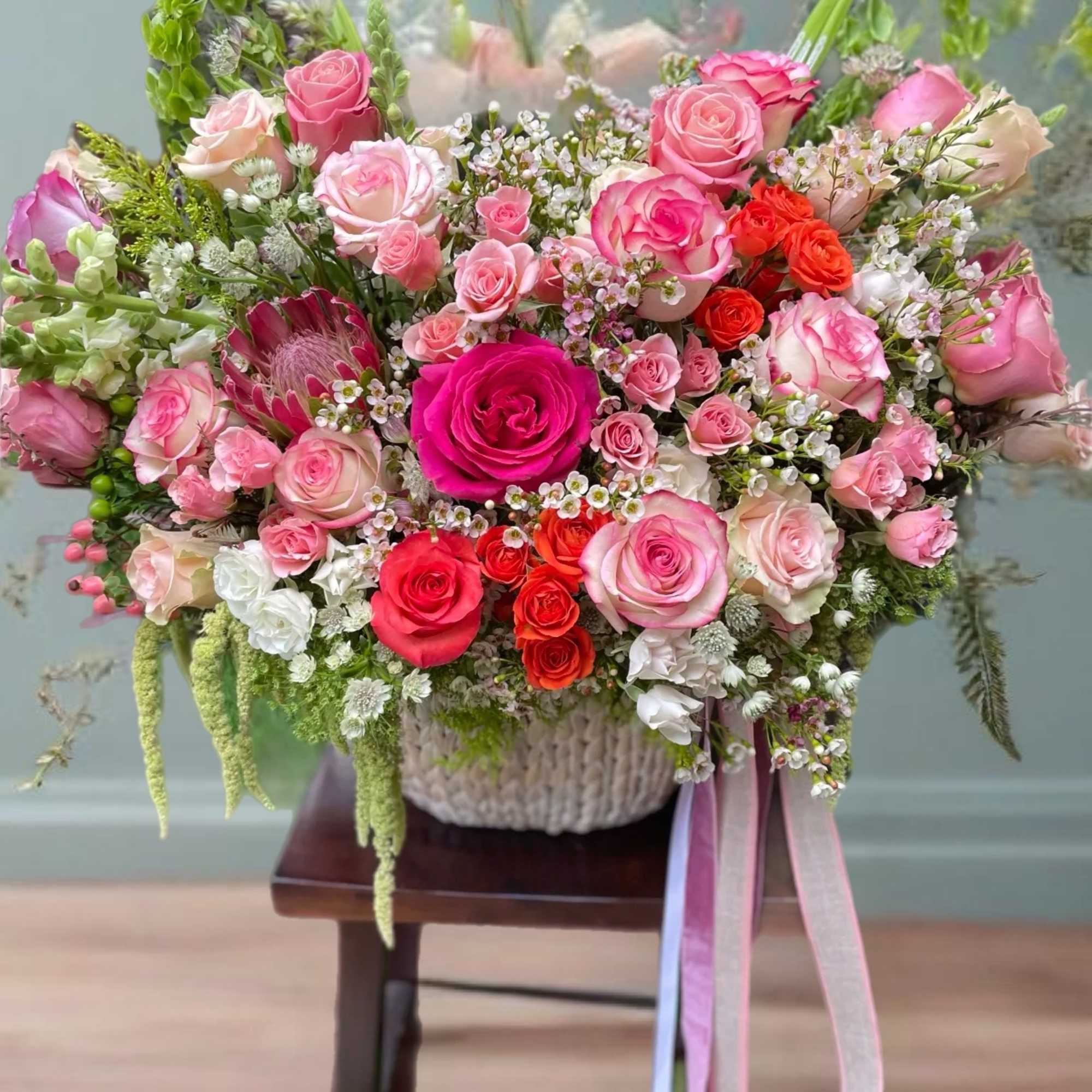 Large bouquet of pink and red roses in a woven basket