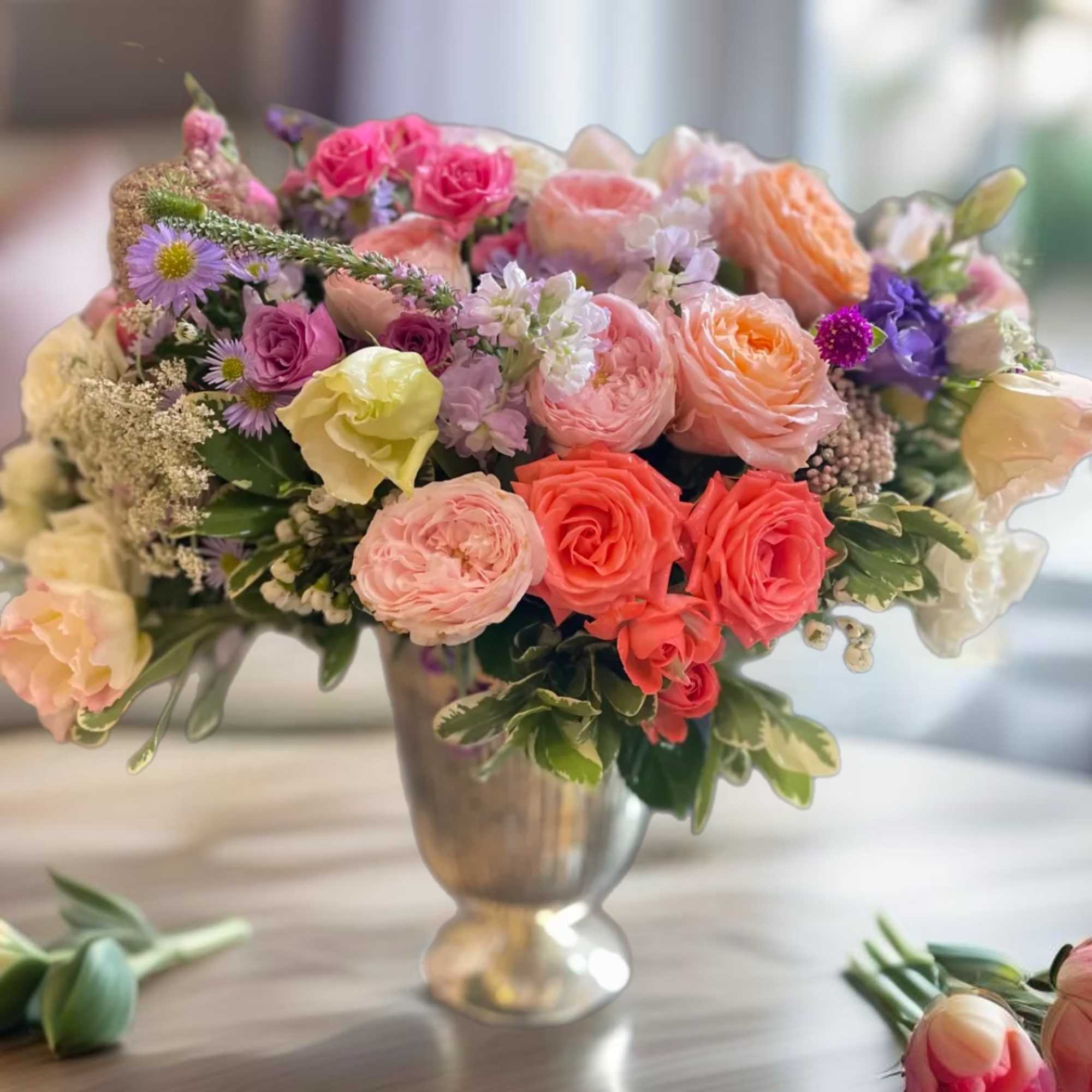 Mixed pastel bouquet in a silver vase with roses and small purple flowers