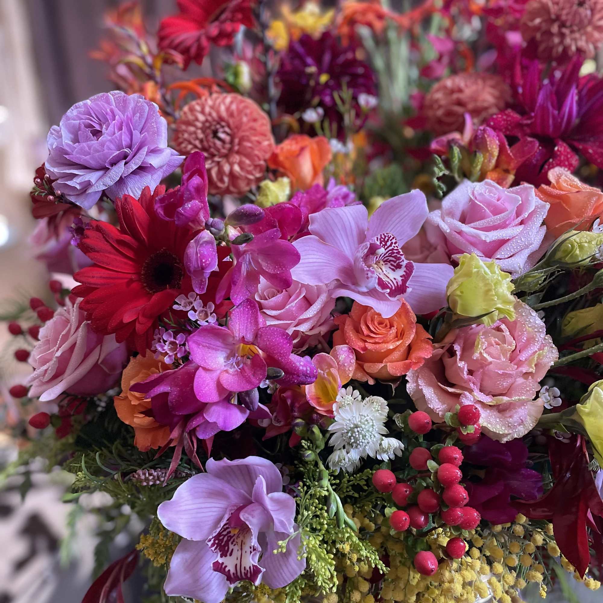Colorful bouquet with pink roses, orchids, and red daisies