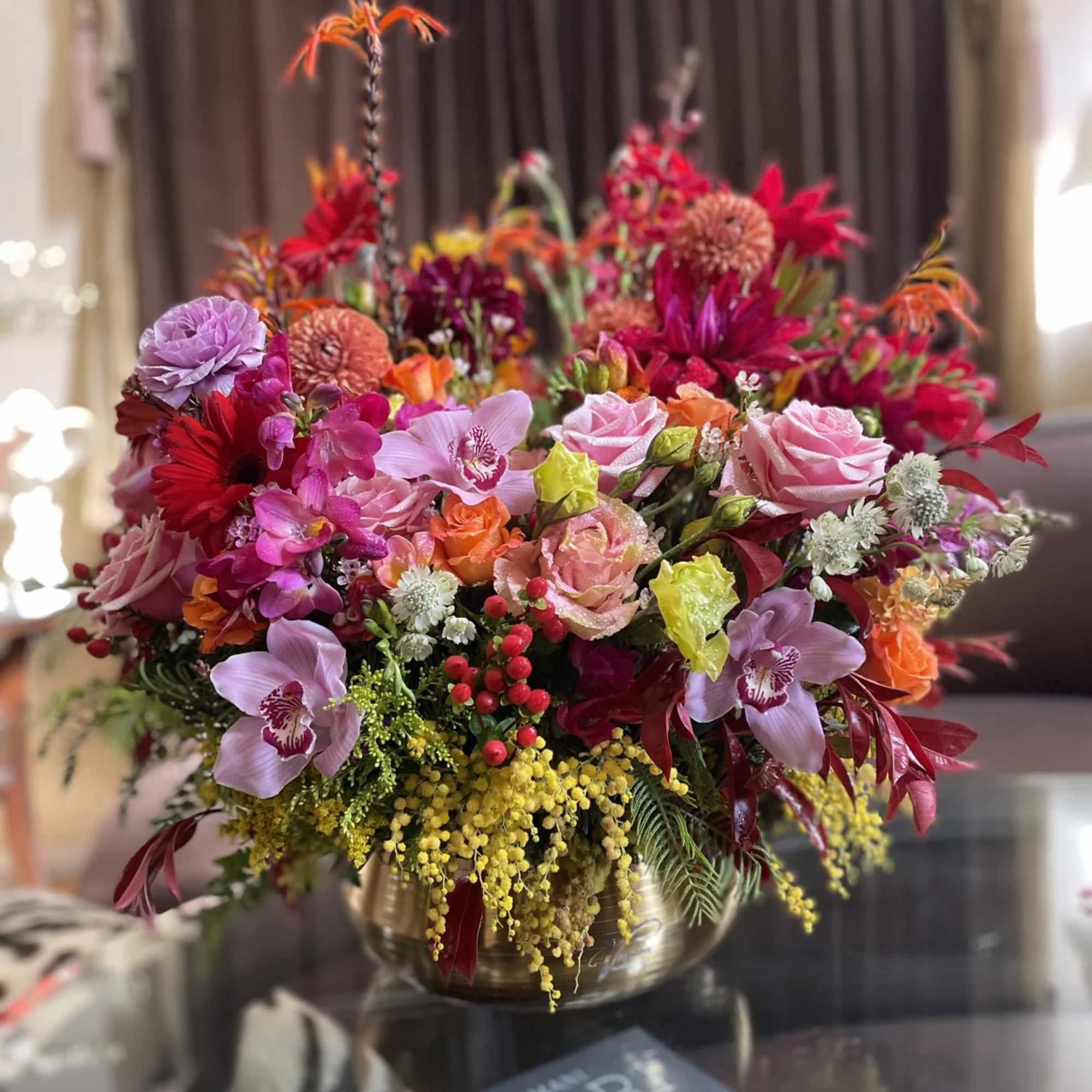Colorful mixed flower arrangement in a round vase on a table