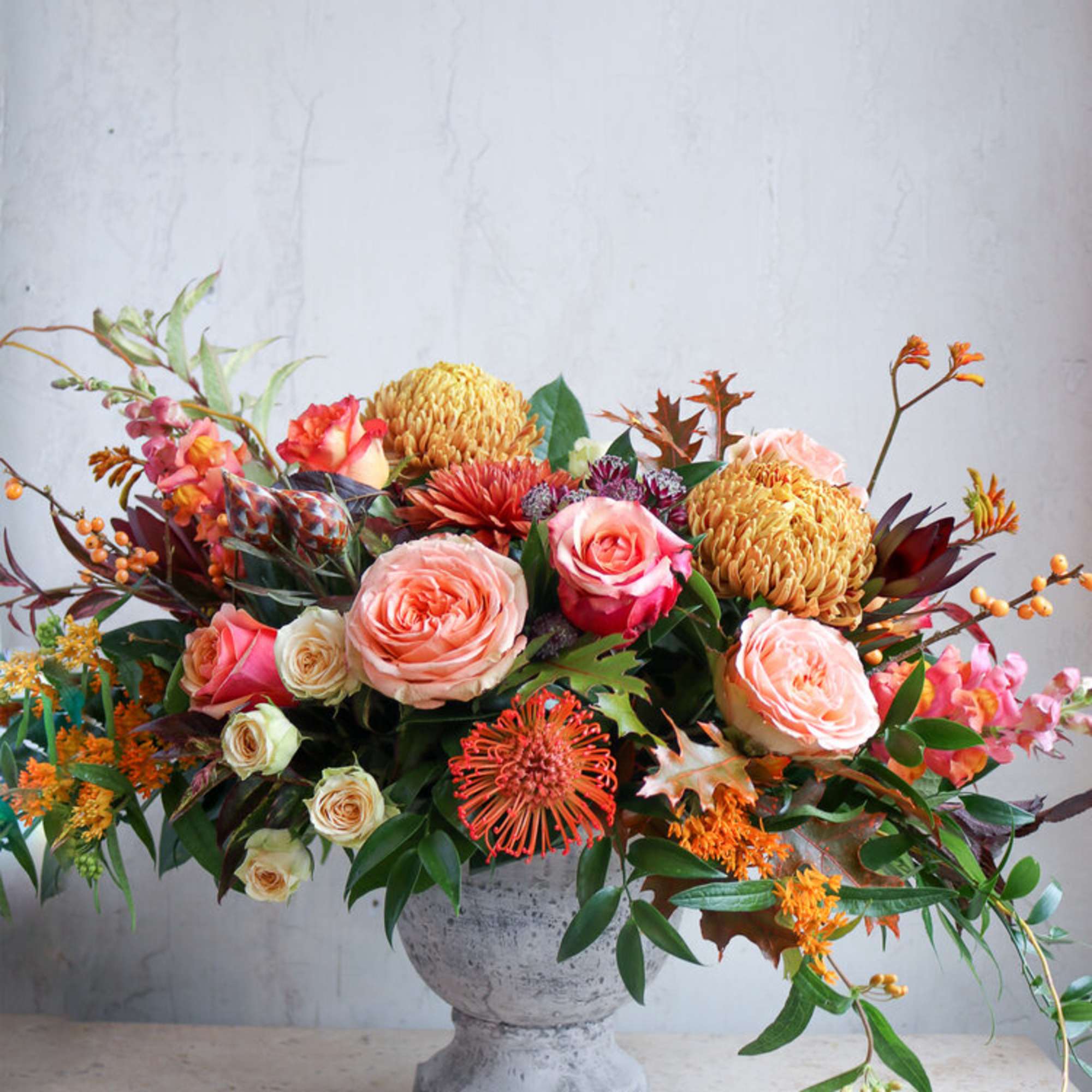 Mixed floral arrangement in a gray urn vase with pink and orange blooms