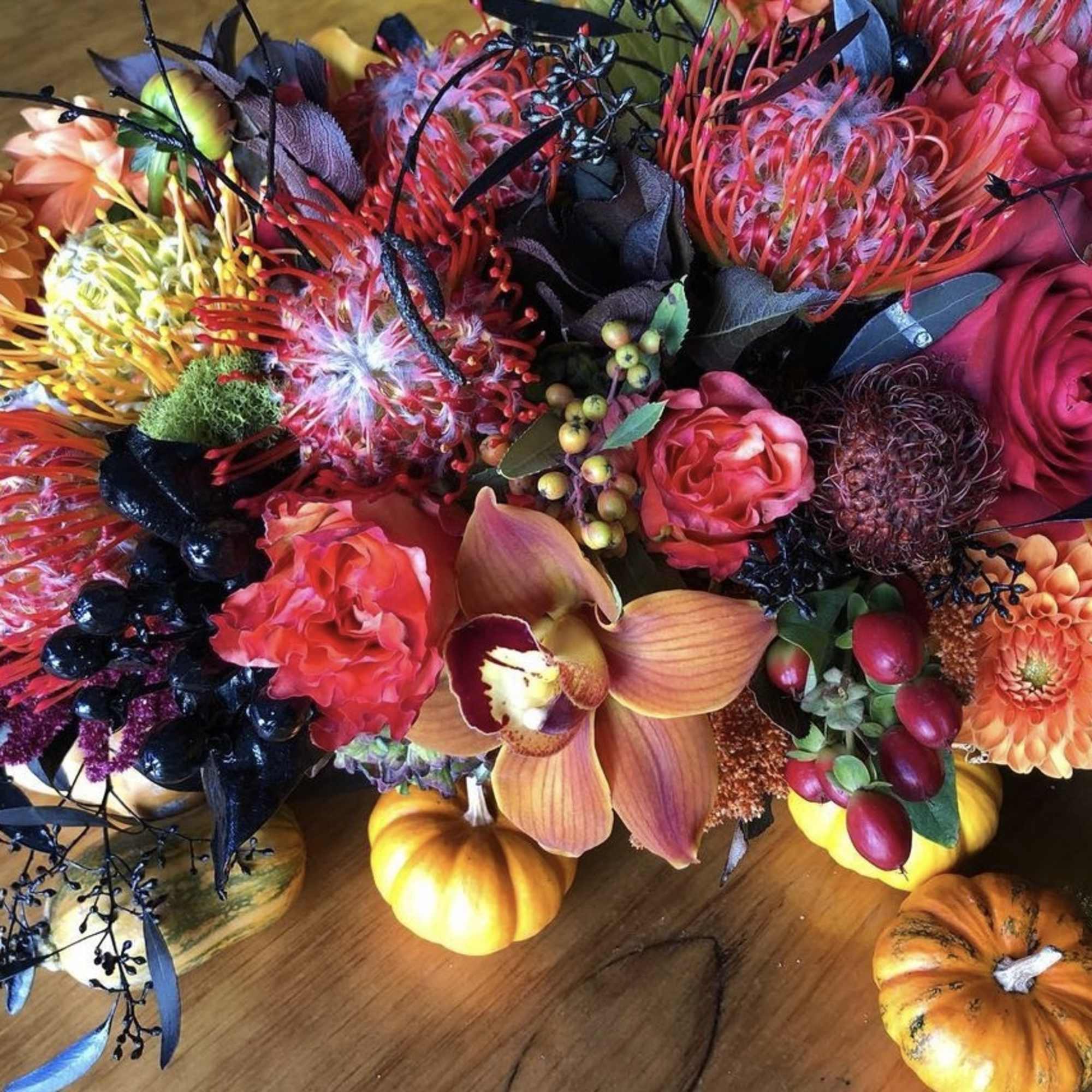 Colorful floral arrangement with orange dahlias, pink roses, and orchids
