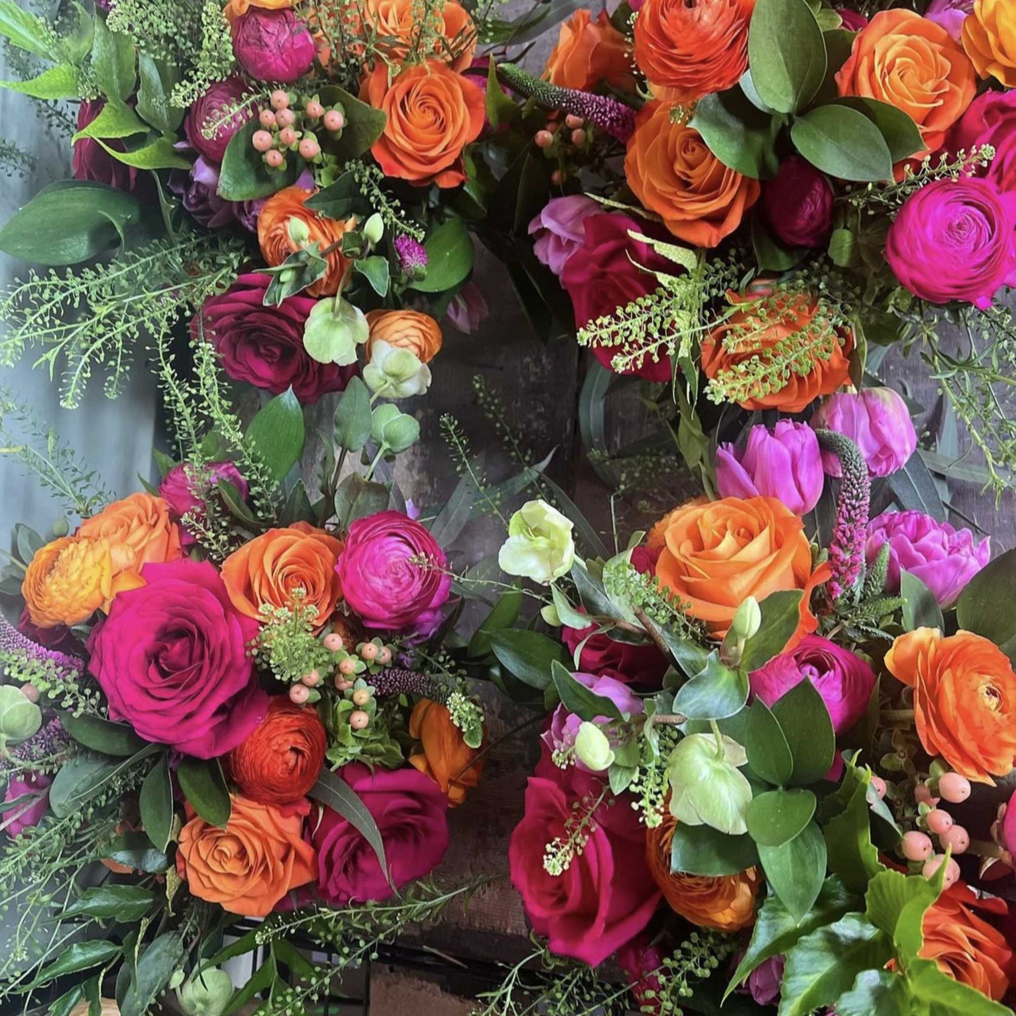 Bright bouquets of orange, pink, and purple roses with greenery