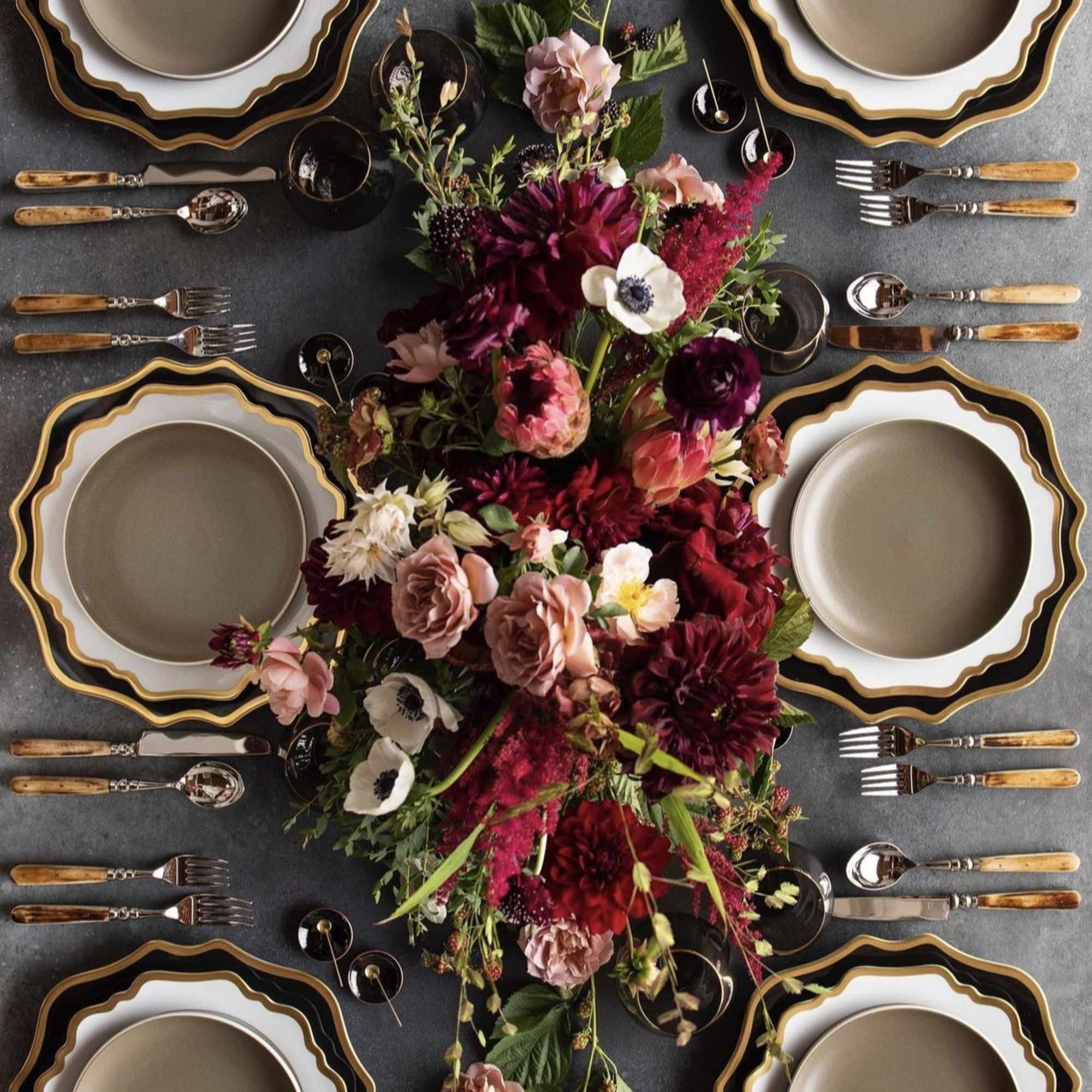 Floral centerpiece with burgundy and blush flowers on a set dining table