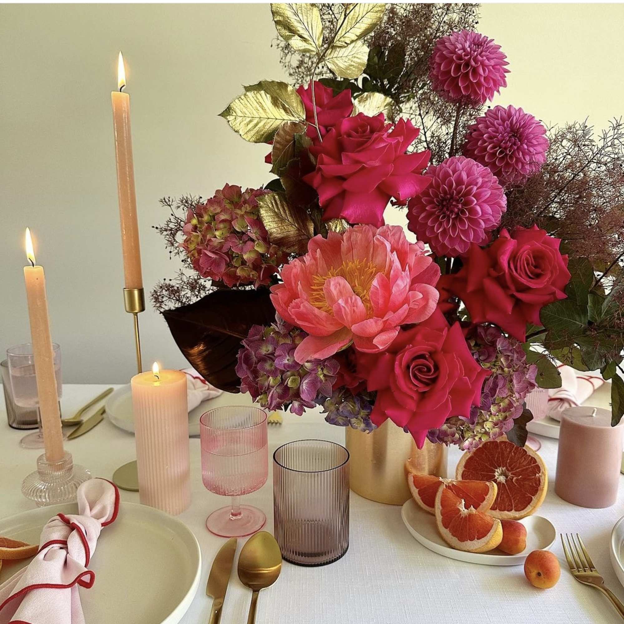 Pink and red floral centerpiece with candles on a table