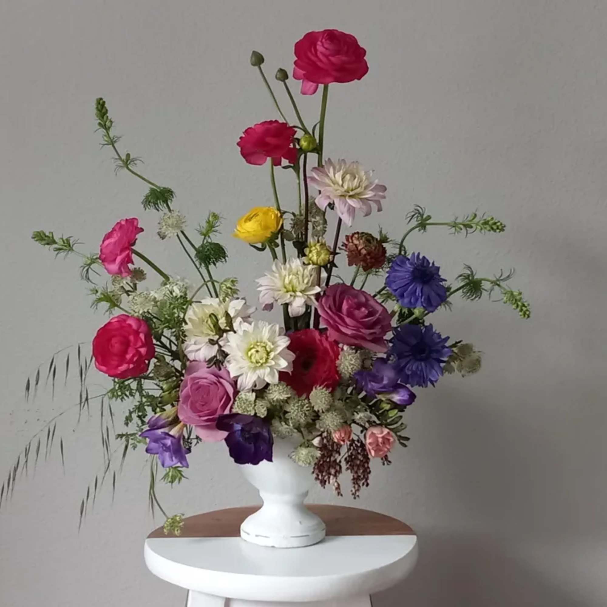 Tall mixed bouquet in a white vase with pink, purple, yellow, and white blooms