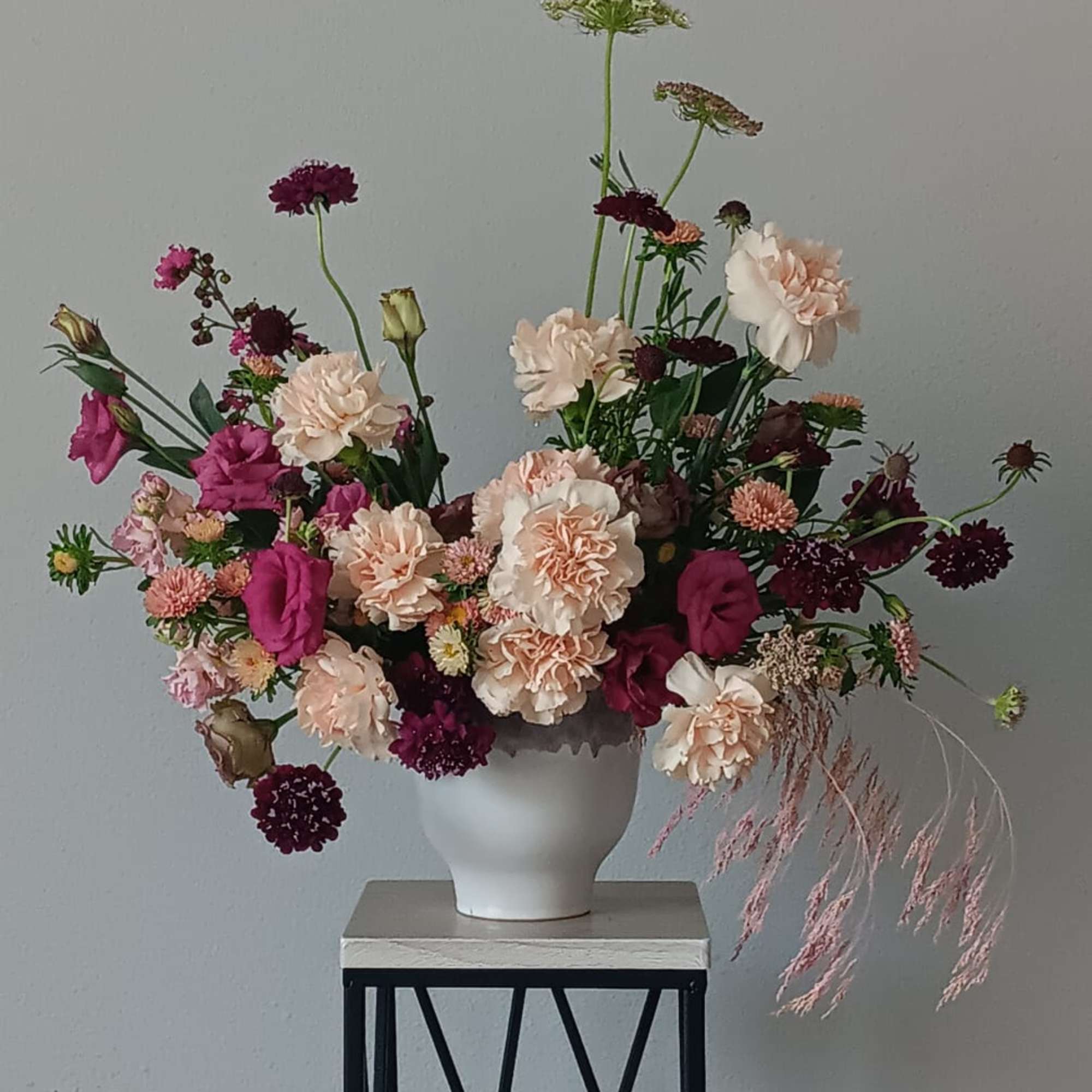 Loose bouquet of pink and cream flowers in a white vase