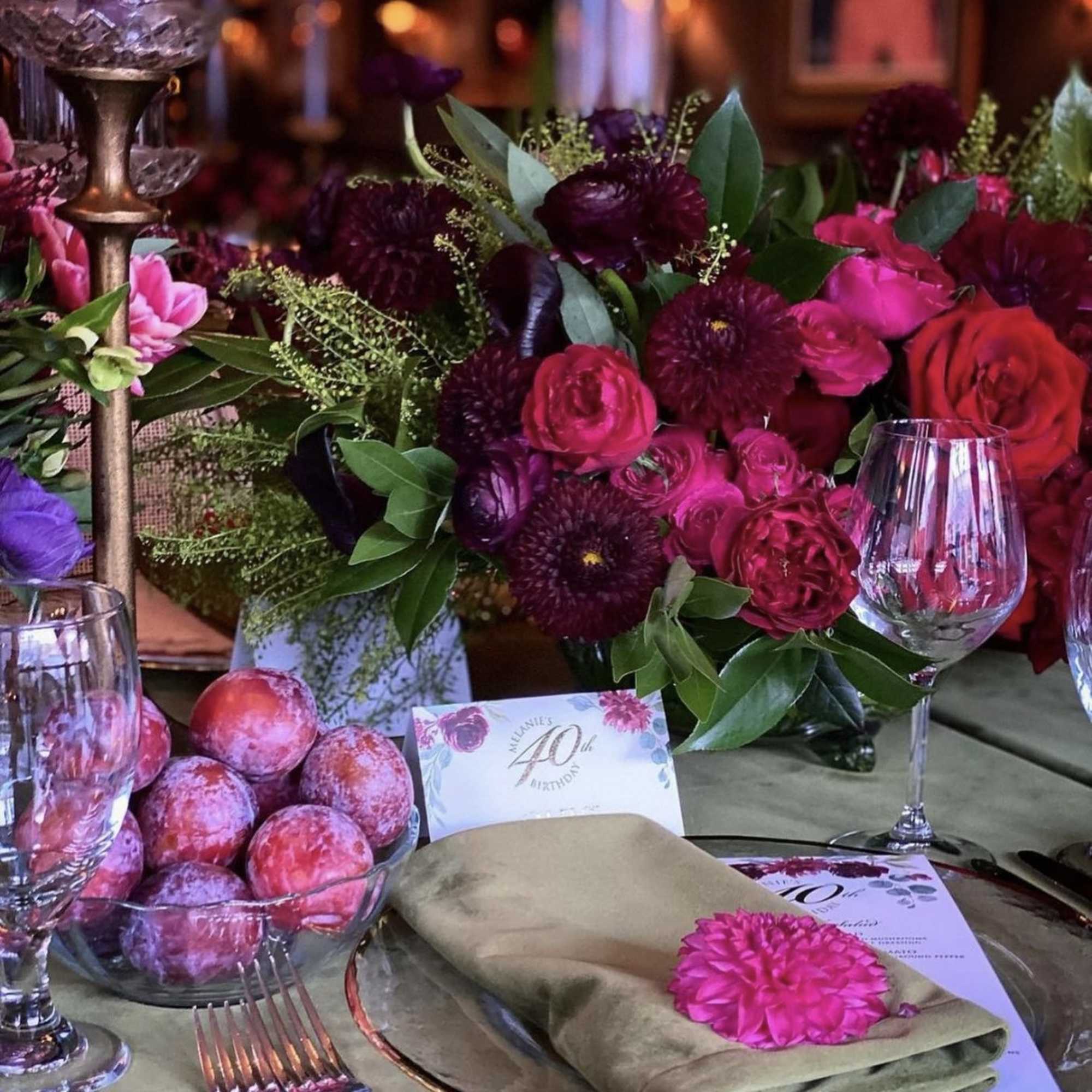 Pink and burgundy floral centerpieces on a decorated table with glassware