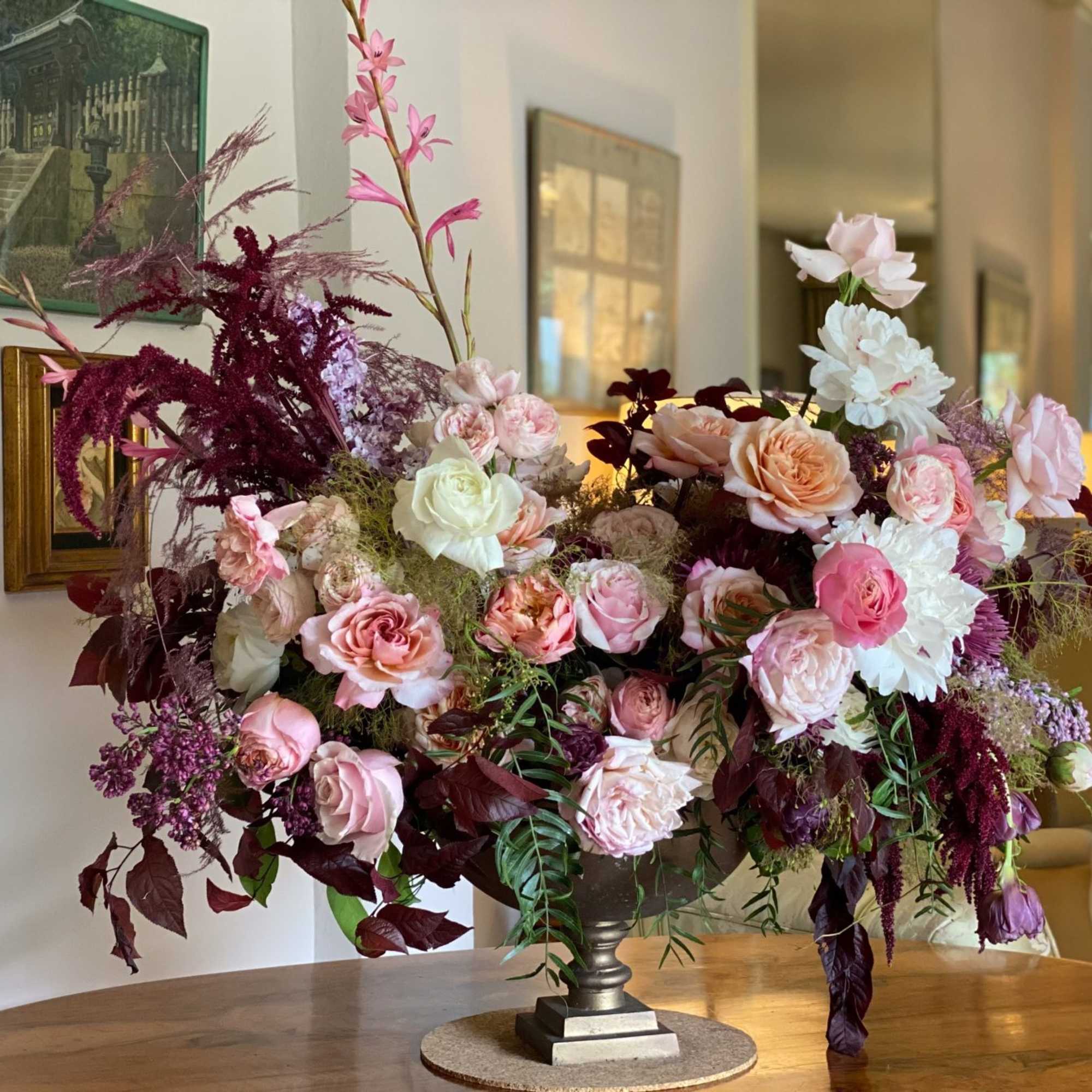 Large pink and white floral arrangement in a silver pedestal vase