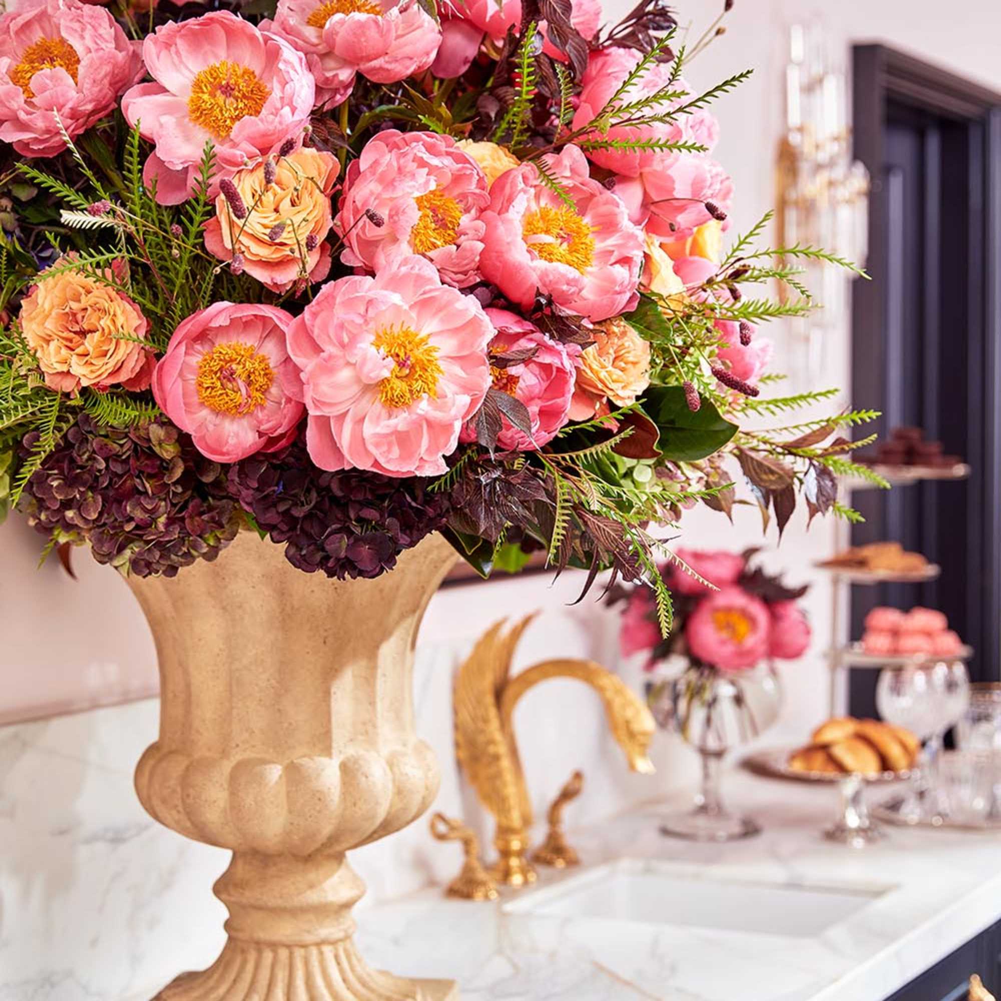 Large pink floral arrangement in a beige pedestal vase