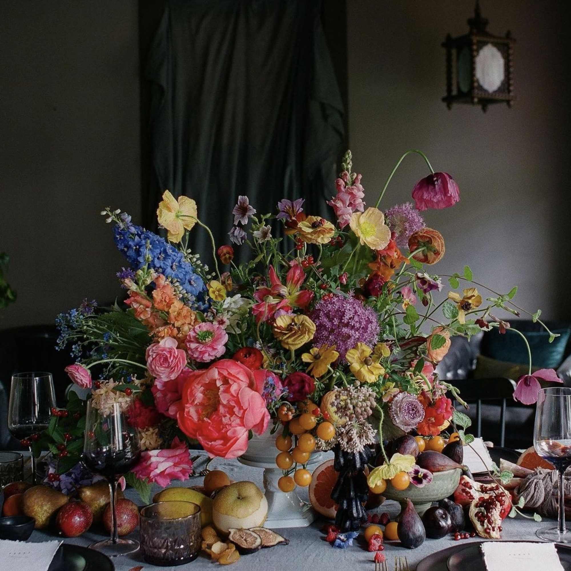 Large colorful floral centerpiece with fruit on a dining table